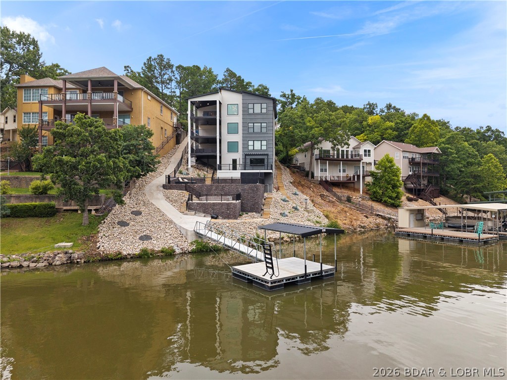 Experience luxury lakefront living in this fully furnished, turnkey masterpiece with stunning stucco and stone curb appeal. Professionally designed by Hockman Interiors, this exceptional home offers 8 bedrooms, 6.5 baths, four levels of living space, & breathtaking 17 MM lake views with the protection of a quiet cove. Thoughtfully designed for entertaining, enjoy the indoor/outdoor bar lounge with custom concrete countertops, 85" TV, saltwater pool, firepit patio with custom concrete seating, game room, & spacious covered decks on every level. The gourmet kitchen features a dramatic waterfall island, Bespoke European glass appliances, butler's pantry, quartz and granite countertops, & designer lighting throughout. The luxurious primary suite boasts a spa-inspired bath & dream walk-in closet. Additional highlights include luxury plank flooring, maintenance-free decking, drive-thru garage with double doors & a great swim dock. LOTS of potential here to install your own dream dock with slips up to 48'+ in length. Undeniable prime location by land & water in Osage Beach for daily convenience. Built for unforgettable lake memories and the ultimate waterfront lifestyle.