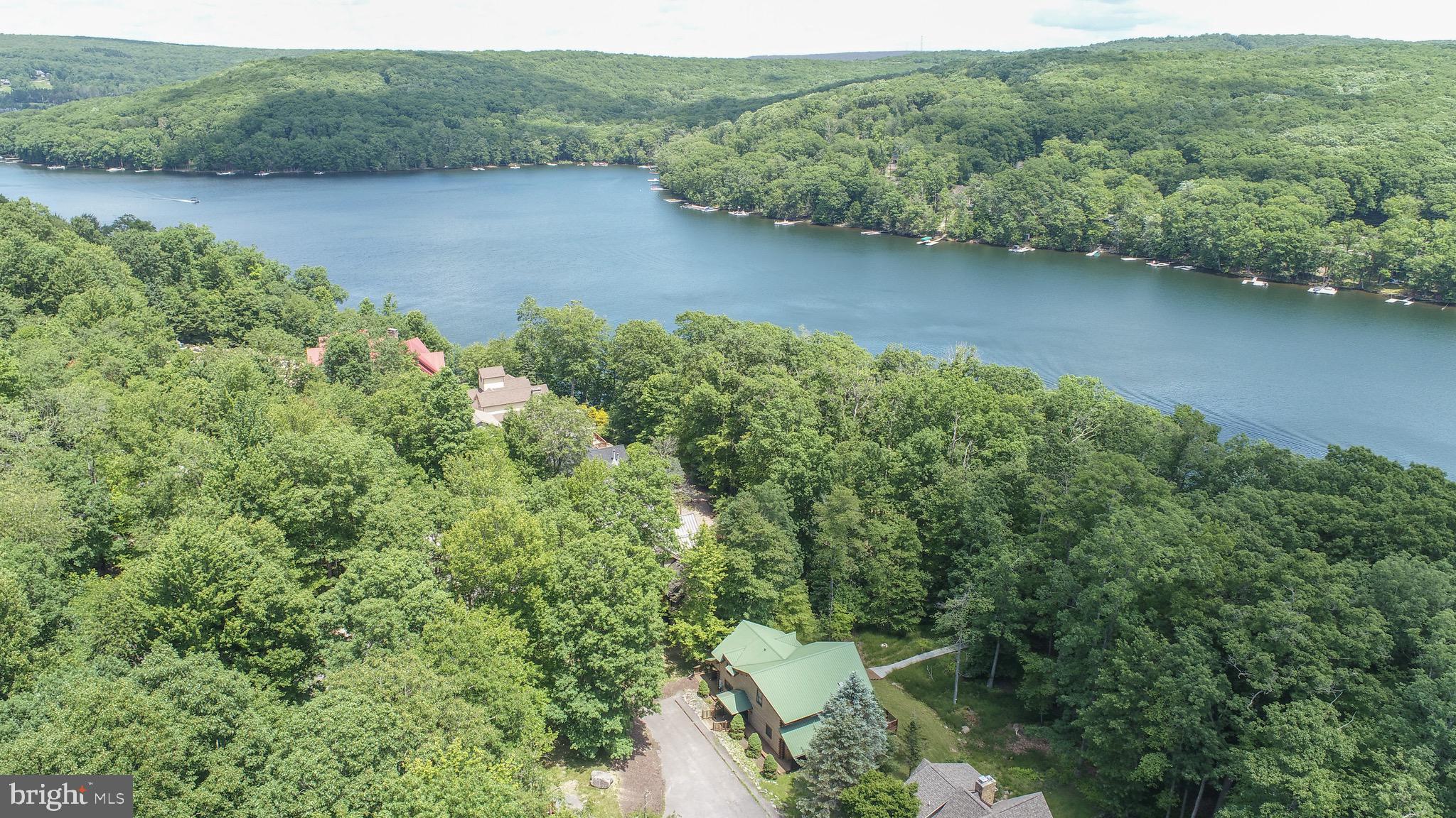 Set in a peaceful, wooded landscape, this stunning lakefront home offers a perfect mix of comfort and natural beauty right in the heart of Deep Creek Lake. With 5 spacious bedrooms and 5 well-appointed baths, this three-level retreat provides breathtaking views from multiple vantage points. The main level features an inviting open-concept design, a gourmet kitchen, and a bright, airy living space that seamlessly connects to expansive decks overlooking the lake. A private Type A dock awaits just steps away, offering the perfect spot for boating, fishing, or simply enjoying the tranquility of the water. The lower level is designed for relaxation and entertainment, complete with a cozy family room, bar area, and walkout access to the outdoors. Each bedroom is a private retreat, while the primary suite offers a spa-like bath and its own balcony. Surrounded by lush trees and the calming sounds of nature, this home is an idyllic lakeside escape, perfect for peaceful getaways or year-round living!