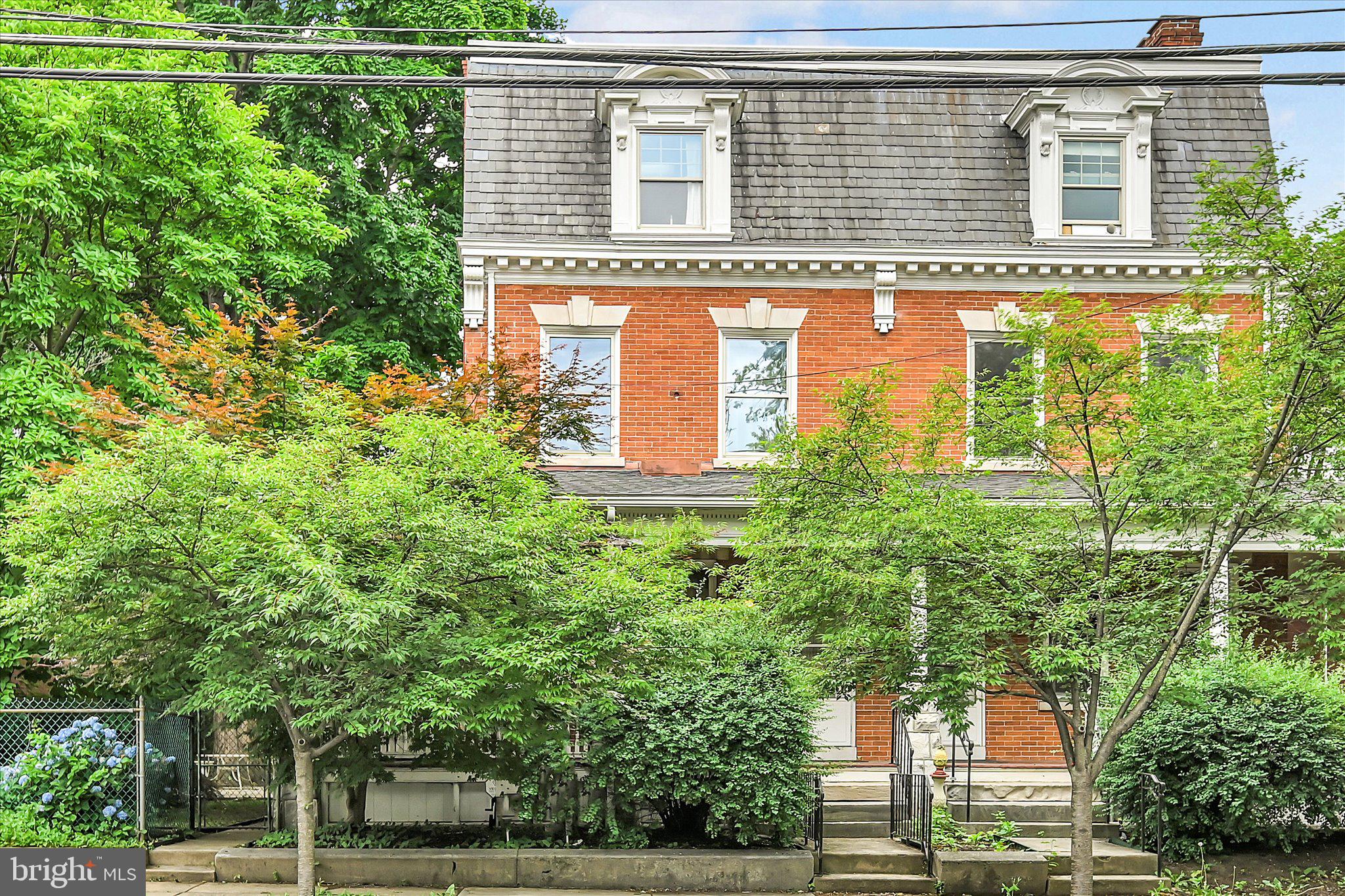 Tucked along one of Lancaster City’s classic tree-lined blocks, 716 N Lime Street blends timeless character with some seriously rare amenities for city living.
This 4-bedroom, 2.5-bath home is full of the charm people love about Lancaster’s historic homes—high ceilings, bow windows, decorative millwork throughout,  warm details, and inviting living spaces—while offering thoughtful updates for everyday comfort. The kitchen has been refreshed and flows nicely into the main living areas, making the home feel both functional and welcoming. One of the most unique features is the second-floor greenhouse, a bright and inspiring space perfect for plant lovers, morning coffee, or a peaceful creative retreat.
Step outside to a private courtyard, ideal for outdoor dining, gardening, or simply enjoying a quiet moment in the city. And then there’s the garage — something you almost never see in Lancaster City. With over 1,300 square feet, this incredible space can comfortably accommodate 4+ vehicles and offers endless possibilities for hobbyists, collectors, or workshop space. With minor modifications, it could even accommodate an RV-sized bay. If you’ve been searching for a Lancaster City home that offers historic charm plus truly exceptional garage space, this one is a rare find.