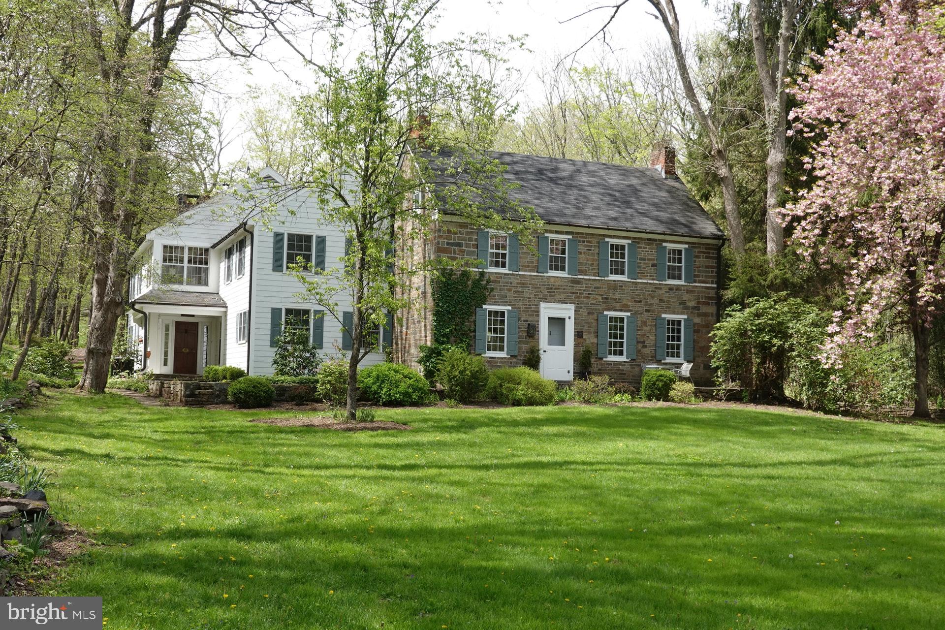 Nestled in the verdant woodlands and fertile farmlands of Upper Bucks County is a classic stone farmhouse full of heart and history. Turn down the winding driveway, over the creek that babbles beneath the tall trees, pass the stone bank barn and emerge at an emerald green lawn that stretches before you, revealing an elegant home tucked into the valley. This is the perfect marriage of old and new, of rustic charm and modern convenience. This is Spondon. Named for a small village in England, this c1825 stone house has been expanded to become a spacious and inviting home. A stone patio graces the front of the house, and leads to a large dining room with deep window sills, a built in floor-to-ceiling wood hutch, and two wood-burning fireplaces. The eat-in kitchen is the heart of the home, with exposed wood beams, wood cabinets, stainless appliances, and an open-air pantry. Close by is a central foyer that opens to a grand living room, with a large fireplace flanked by benches, and built-in bookcases. Upstairs, the luxurious master suite features yet another fireplace, walk-in closet, and master bath with a Japanese-style soaking tub. A private master balcony looks out over the creek and back yard, and is the perfect place for morning coffee. Three more bedrooms complete the second floor, along with two full baths, and a finished attic room boasts a walk-in closet for extra storage.  A rear patio gives way to an in-ground pool, just right for hot afternoons or warm summer evenings. The gravel driveway has two parking areas for easy access to both the grounds and the house, with room to accommodate family as well as guests. A 4-story stone bank barn once held horses on the ground level, while upper levels feature a glass wall entry and a spacious and versatile interior with offices, workrooms, a cedar closet, and multiple loft areas.  For the adventurous, 88 acres of woods and fields invite exploration and discovery, with endless opportunity for hiking or recreation. Hidden away in coveted Tinicum Township, Spondon is nevertheless in easy driving distance to town centers, and just a few short minutes from scenic River Road. Classic Bucks County living at its finest, in the most enchanting of settings, Spondon is a timeless yet unique property.