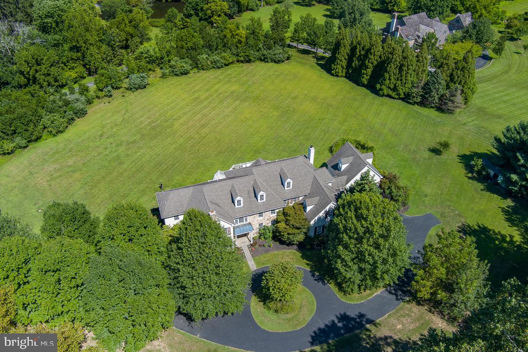 Welcome to 2 Spring Meadow Farm Lane — a spacious and elegant 5+ bedroom, 5+ bathroom home tucked away in a quiet Charlestown Township cul-de-sac. Set on 3.78 level, open acres in a small community of high-end homes, this property offers privacy, functionality, and exceptional living space inside and out. With over 6,000 square feet across the first two floors, the home features hardwood floors, generous room sizes, high ceilings, and large windows showcasing peaceful views. The main level includes a fireside living room, formal dining room, private office, sunroom (or second office), and a chef’s kitchen with granite countertops, stainless steel appliances, a center island, and a breakfast area — open to a spacious family room with a stone fireplace. Access the rear deck from several rooms, perfect for entertaining or relaxing outdoors. The first floor also includes two half baths and a practical mudroom. Upstairs, the primary suite consists of a sitting room, two walk-in closets, a tray ceiling, and a spa-style bathroom. Four additional bedrooms feature two en-suite bathrooms plus a Jack & Jill bath. The laundry room is conveniently located on this level, with stair access to an unfinished third floor for storage or future use.
The finished, walk-out lower level features a full bath, a bar area, an open recreation space, and additional finished rooms—ideal for a gym, a hobby area, or accommodating guests. Car enthusiasts will appreciate four garage bays: two attached and two in a detached garage with a walk-up loft space ready to be customized. The property is located in the award-winning Great Valley School District, offering easy access to the PA Turnpike, Paoli train station, shopping, and parks.