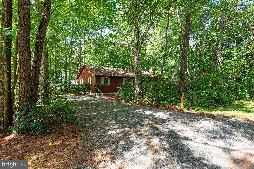 Welcome to this charming 3-bedroom, 2-bath home in the heart of Ocean Pines, sitting well back from the road and surrounded by natural beauty! Gently used as a vacation home by the owner for many years, this property has been very well maintained, with service contracts on all major systems for peace of mind. A new roof was added in 2019, newer windows providing efficiency and comfort, newer protective gutter guards, and storage is abundant with a pull-down attic with flooring.  Tucked away in a tranquil wooded setting, this home offers fantastic privacy while still being close to everything the Eastern Shore has to offer.  There’s ample room to build a garage or park your boat here, giving you great options to expand (see updated survey).  Inside, you’ll find spacious bedrooms and a warm living area complete with a cozy fireplace—perfect for relaxing evenings or gathering with friends. The open layout creates excellent entertaining space, while the front porch, back deck and patio, and outside shower (with both hot and cold water) invite you to enjoy coastal living at its best.  This home truly combines comfort, convenience, and community—ready for you to make it your own!  Ocean Pines amenities are second to none, including: five pools, a racquet center with pickleball, tennis & paddle courts; several kayak launches; a yacht club with dining and a marina, and many parks right at your fingertips. Beyond the neighborhood, you’re just minutes from the historic town of Berlin, MD, and a short drive to the beaches of Ocean City and Assateague.