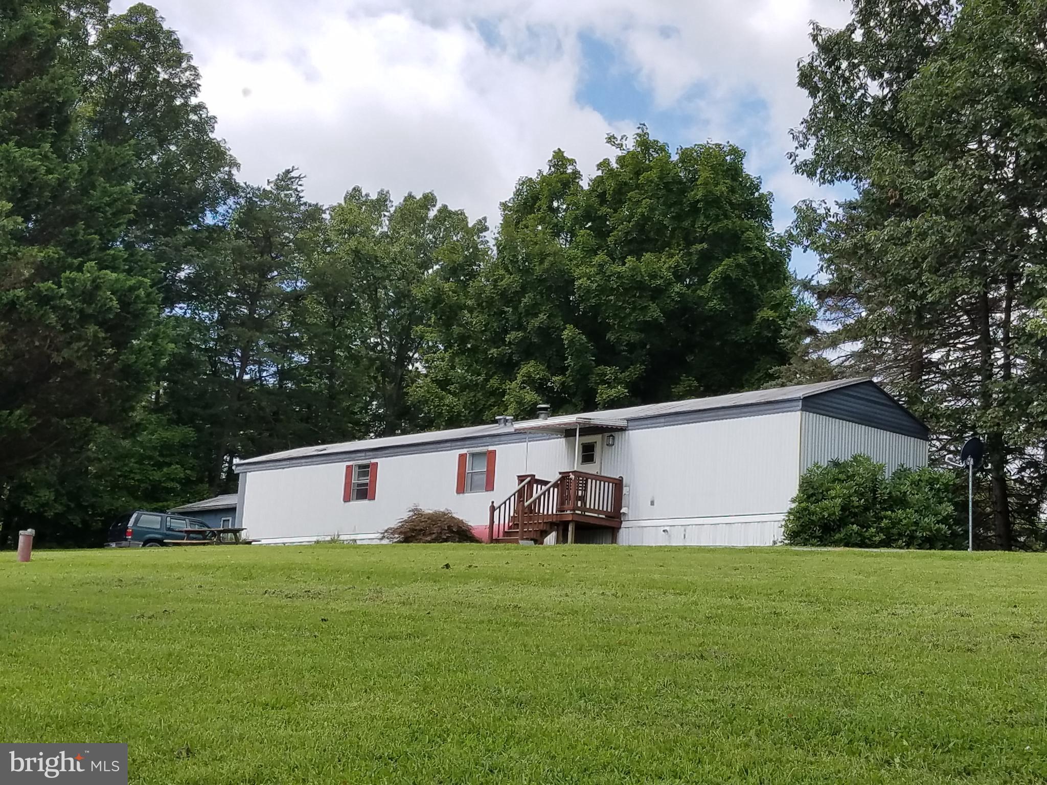 2 lots totaling 14.71 unrestricted acres with about 5 acres open pasture and the balance in hardwoods. Property has a pond and small barn with stalls.  Animals welcome. Older 2 bedroom/1 bath livable mobile home is currently rented, could live in it while building a new home. Nice views from the hill overlooking the town of Berkeley Springs, close to I-70 for easy commute to points east and west.  Plenty of space for gardening, horses and other farm animals welcome.