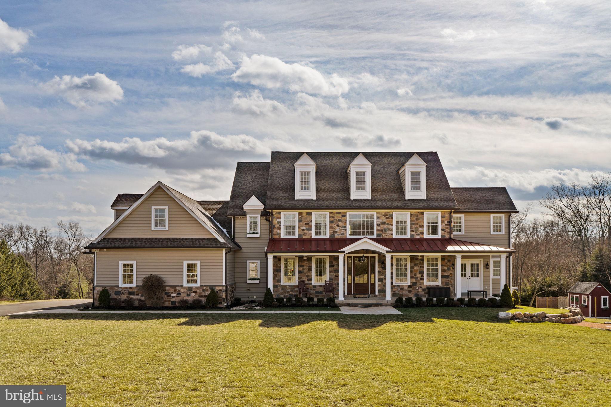 Welcome to a home where elegance and craftsmanship come together, set on a breathtaking 3-acre property in one of Newtown's most sought-after locations. This 4-bedroom, 4.5-bathroom home spans over 5,000 square feet, offering a masterful blend of luxury, comfort, and modern convenience. As you arrive, a long private driveway winds its way to the front of the home, revealing an architectural masterpiece. The exterior showcases timeless natural stone accents and an inviting porch with a standing seam metal roof—perfect for taking in the serene views of the surrounding landscape. Enter through the stately solid mahogany front door into the grand two-story foyer, where wide-plank oak flooring and a graceful Juliet balcony set the tone for this extraordinary residence. The thoughtfully designed floor plan seamlessly balances sophisticated entertaining spaces with the comfort of everyday living. The heart of the home is the stunning great room, highlighted by reclaimed barn wood beams, a natural stone gas fireplace with a hand-hewn wood mantel, and oversized windows that bathe the space in natural light. Adjacent is the formal dining room, featuring elegant coffered ceilings and cottage-style windows that create a warm, inviting ambiance. For the culinary enthusiast, the chef’s kitchen is nothing short of spectacular. It boasts custom Starmark cabinetry, expansive granite countertops, and professional-grade appliances, including a dual-fuel range, vent hood, warming drawer, and not one but three SubZero refrigerators. The oversized farmhouse sink and fully equipped prep pantry elevate this space to a true culinary haven. Nearby, the butler’s pantry offers added convenience with an ice maker, instant hot/cold water dispenser, and a charming Nantucket sink. Practicality meets style in the mudroom, where custom-built storage cubbies, a pet shower, and a secondary laundry area make day-to-day living effortless. For remote work or quiet study, the private office with sliding barn doors offers the perfect sanctuary. Upstairs, each of the four spacious bedrooms is designed with both comfort and style in mind. Three full bathrooms on this level feature luxurious finishes, while the media room—complete with a 100” screen and state-of-the-art surround sound—provides the ultimate entertainment experience. A second laundry room, equipped with dual hookups, soundproof drywall, and a waterproof floor system, adds unparalleled convenience. The lower level offers endless possibilities, with its own private entrance and a finished full bathroom, making it ideal for a home office, gym, or future in-law suite. The third level, already framed and floored, is a blank slate ready for customization. Car enthusiasts will appreciate the oversized 4-car garage, featuring insulated doors and a durable polyaspartic epoxy floor. The home is equipped with a Kohler liquid-cooled whole-house generator, ensuring peace of mind in any weather. Outside enjoy the professionally designed backyard oasis. A custom fire pit with natural stone boulders and a bluestone deck creates the perfect setting for outdoor gatherings. The expansive yard provides a peaceful escape, surrounded by lush greenery and endless opportunities for recreation or relaxation. This exceptional property offers a rare combination of luxurious amenities, unparalleled craftsmanship, and natural beauty—all in the heart of Newtown. Don’t miss the chance to make this one-of-a-kind home your private sanctuary.