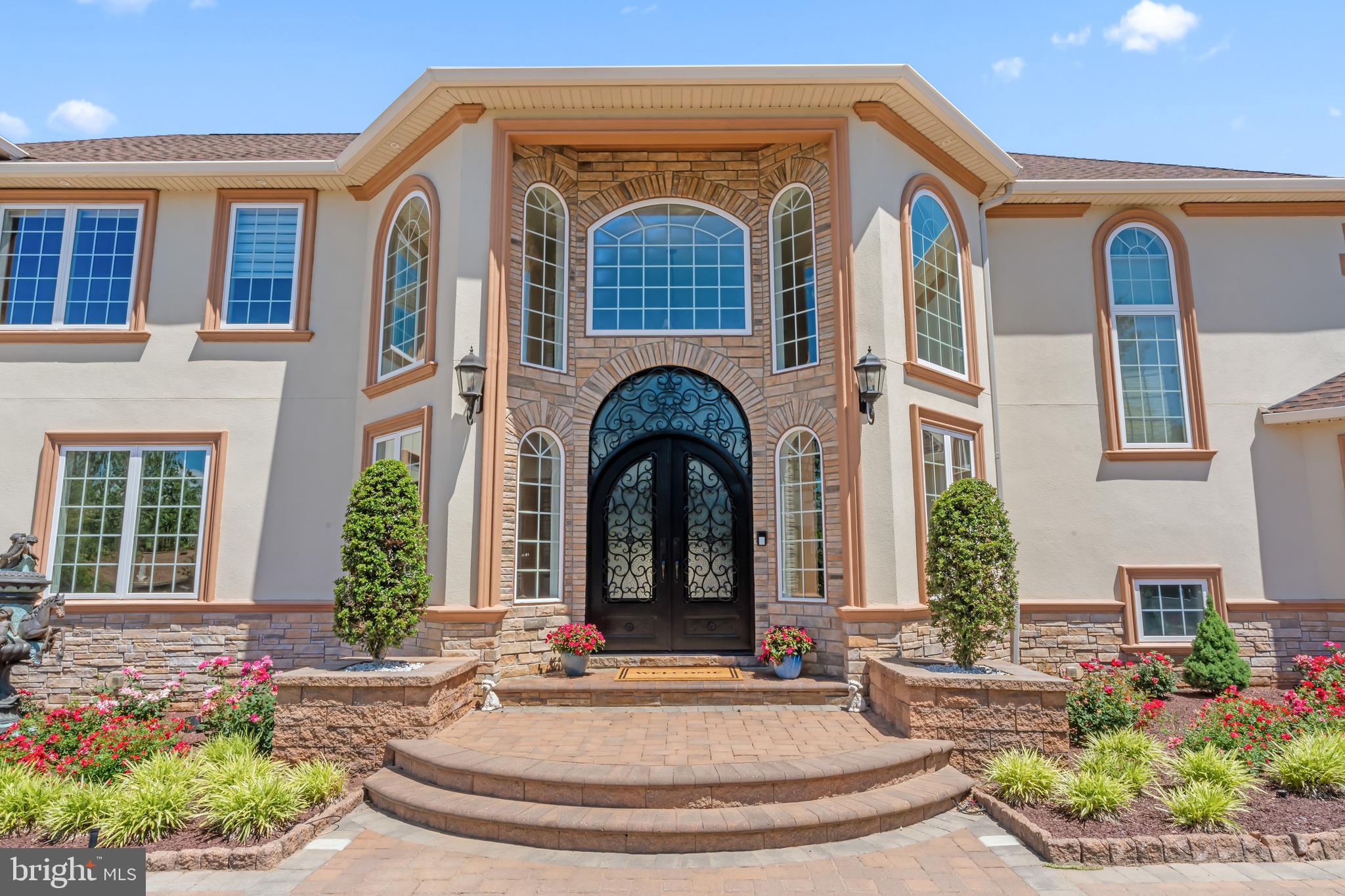 1066 Washington Crossing Road, Newtown, PA is one of the most extraordinary private estates ever offered in Bucks County. This fully gated and entirely fenced custom residence spans nearly 10,000 square feet of refined living space, offering approximately 8,000 square feet above grade plus an additional 2,000 square feet of finished lower-level living. Designed without compromise and built with no expense spared, the home delivers a rare combination of privacy, architectural significance, and lifestyle versatility within Upper Makefield Township.

The residence features six bedrooms plus a dedicated office, six full bathrooms and three half bathrooms, and an exceptionally rare open-concept floor plan that seamlessly connects grand-scale entertaining with everyday living. From the moment you enter, the home impresses with soaring ceilings, hand-crafted millwork, ornate plaster detailing, marble floors, and dramatic chandeliers—timeless details that reflect true custom craftsmanship throughout. The showpiece kitchen anchors the home and flows effortlessly into expansive dining and living spaces designed to host at the highest level.

A standout feature of the property is the expansive in-law suite, which functions as a home unto itself and offers two bedrooms, two and a half bathrooms, a full kitchen, and a private laundry room—ideal for multi-generational living, extended stays, or guest accommodations. In total, the home includes three separate laundry rooms for maximum convenience. Additional lifestyle amenities include a climate-controlled wine cellar, a half indoor basketball court, a beautifully designed outdoor pergola, custom garage space, and thoughtfully finished lower-level living areas that further enhance the estate’s functionality.

Built for comfort, security, and peace of mind, the home is equipped with a full-house generator supported by a 1,500-gallon underground propane tank, allowing the property to operate off-grid for extended periods if necessary. A state-of-the-art smart-home security system integrates cameras, gated entry controls, lighting automation, and advanced monitoring throughout the estate. Whole-home surround sound music systems extend through virtually every room, creating a fully immersive and connected living experience.

Additional highlights include five walk-in closets, a dedicated home office, and a layout that perfectly balances grandeur with warmth and livability. Located in the highly sought-after Council Rock School District and just minutes from the charm of Newtown, this is more than a residence—it is a legacy estate offering privacy, scale, and craftsmanship that simply cannot be replicated.