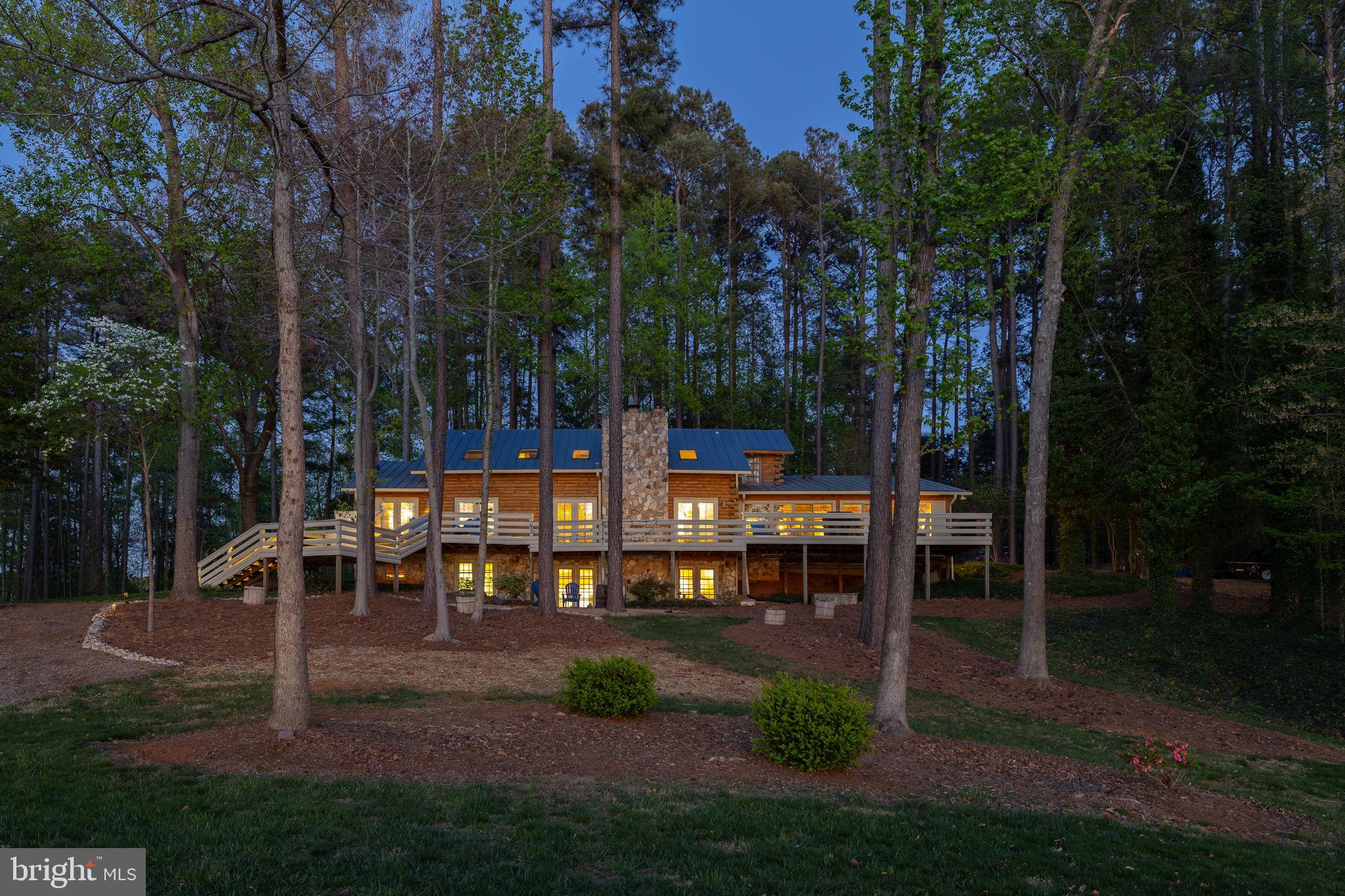 A true waterfront retreat at Lake Anna, Virginia—this extraordinary custom-built log home offers the ultimate in resort-style living. Ideally situated on the southern end of the lake, where the waters are wide, open, and pristine, this property is nestled within the gated Fisherman’s Cove community on the public side of the lake. Offered fully furnished and turn-key, with high-speed Xfinity/Comcast internet available, this is a rare opportunity to step right into luxury lake living. Set on two waterfront lots totaling approximately 2 acres with the potential to build a separate guest house, the property features an incredible 1,300 feet of riprap shoreline and breathtaking western sunset views. Designed for recreation and relaxation, the outdoor amenities are unmatched. Enjoy two boathouses—one featuring two slips with electric lifts, and the other offering a covered slip, cabana, sundeck, and gazebo. There is also a patio for dining down by the water. A waterside sports court is perfect for basketball or pickleball, while multiple fire pit areas create inviting spaces to gather and unwind. Inside, the home is a true masterpiece of craftsmanship, blending rustic charm with upscale finishes. Highlights include 6-inch heart pine hardwood floors, hand-hewn cedar moldings and baseboards, cedar-lined closets, and hand-selected Georgia fieldstone. Three gas fireplaces and soaring vaulted ceilings add warmth and character throughout. A new metal roof (2018), newer upstairs HVAC unit (2022) and two propane water heaters (2025) add peace of mind. The gourmet kitchen is designed for entertaining, featuring custom handcrafted cabinetry, granite countertops, a massive island, a 6-burner gas stove, beverage coolers, a separate prep sink, built-ins, and a stylish wet bar/coffee bar—all seamlessly open to the family room and dining area. The main-level primary suite is a private retreat, complete with a raised gas fireplace, direct access to the full-length lakeside deck, and a luxurious ensuite bath with a soaking tub, separate vanities, a tiled walk-in shower, and a sauna. An additional main-level bedroom offers direct access to a full bath, while a sunroom with sliding doors provides the perfect place to take in the lake views year-round. Upstairs, the loft features a cozy reading nook with built-in bench seating and shelving, along with three additional bedrooms and two full baths. The lower level is designed for entertainment and comfort, offering a spacious family room, recreation area, movie room, full bath, laundry, and storage. Additional features include a paved driveway and a spacious two-car attached garage, offering both convenience and ample storage. Outdoor living continues with a massive back deck, patio, and thoughtfully designed gathering spaces throughout the property. A rare offering on Lake Anna, this one-of-a-kind retreat is ideal as a personal escape, full-time residence, or investment opportunity—short-term rentals are permitted, making it an exceptional find and an even sweeter deal!
