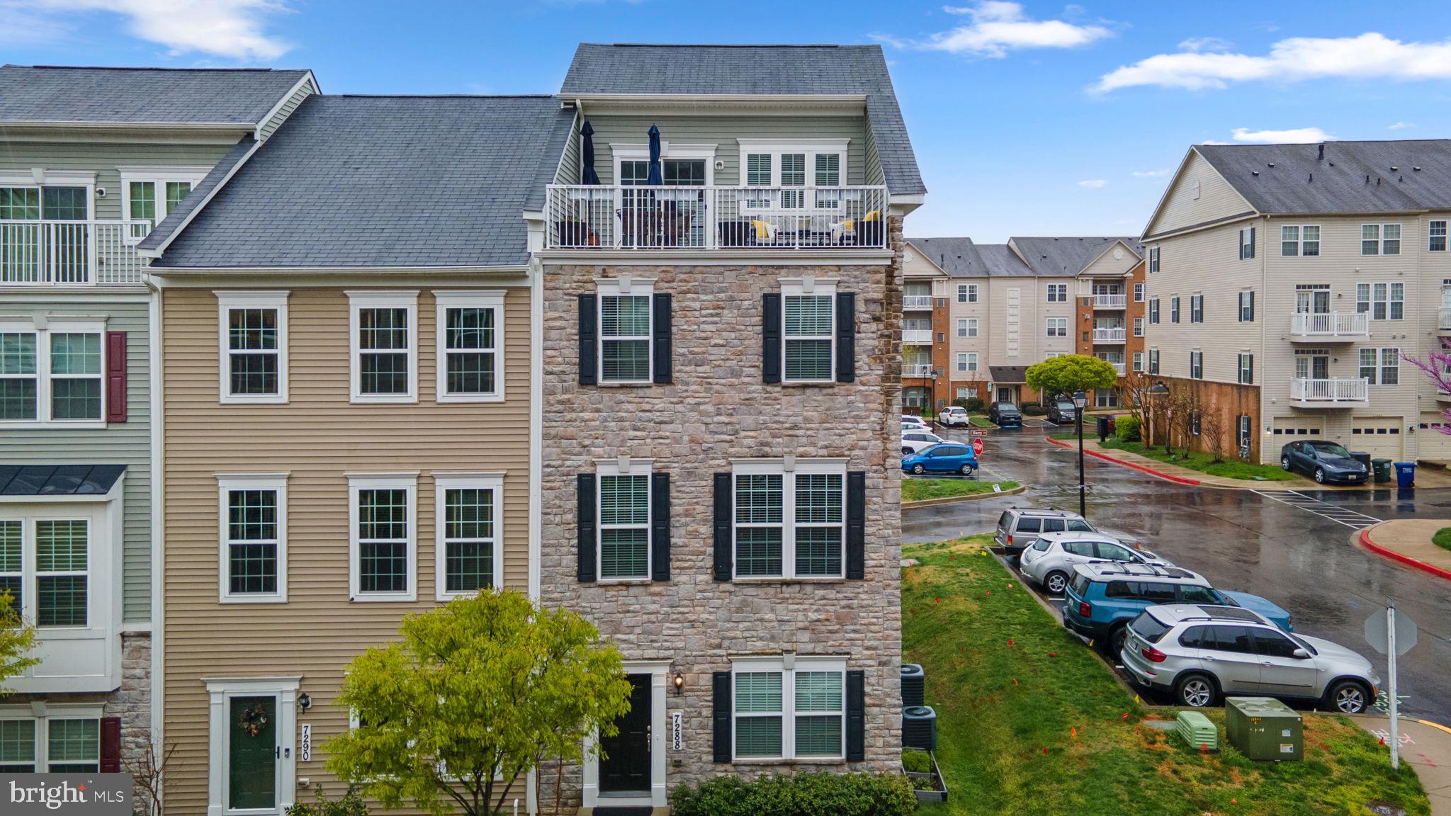 Stunning stone-front end-of-row townhouse offering 2,276 square feet, featuring 3 bedrooms, 2 full bathrooms, 2 half baths, and a spacious 2-car garage in sought-after Elkridge Crossing. The fully finished entry-level includes a comfortable family room with garage access and walkout access to the exterior. Rich wood floors flow throughout the expansive main level, where a bright, open-concept living room with a stylish powder room connects seamlessly to the kitchen and dining area. A modern chandelier adds a touch of elegance, while sliding doors lead to the rear deck—ideal for entertaining or enjoying your morning coffee. The eat-in kitchen is a chef’s dream, featuring an oversized island breakfast bar with pendant lighting, stainless steel appliances, quartz countertops, a subway tile backsplash, and generous cabinetry for all your storage needs. Upstairs, you'll find two well-appointed bedrooms and a full hall bathroom. The spacious primary suite offers a walk-in closet and a luxurious en suite bath with dual vanities, a large shower with a built-in bench, and a private water closet. The second bedroom also impresses with two walk-in closets. The top-level loft is a versatile space—perfect as a third bedroom or guest suite. It features a half bathroom, a full wet bar with a beverage refrigerator, a laundry area, and access to a private terrace.
