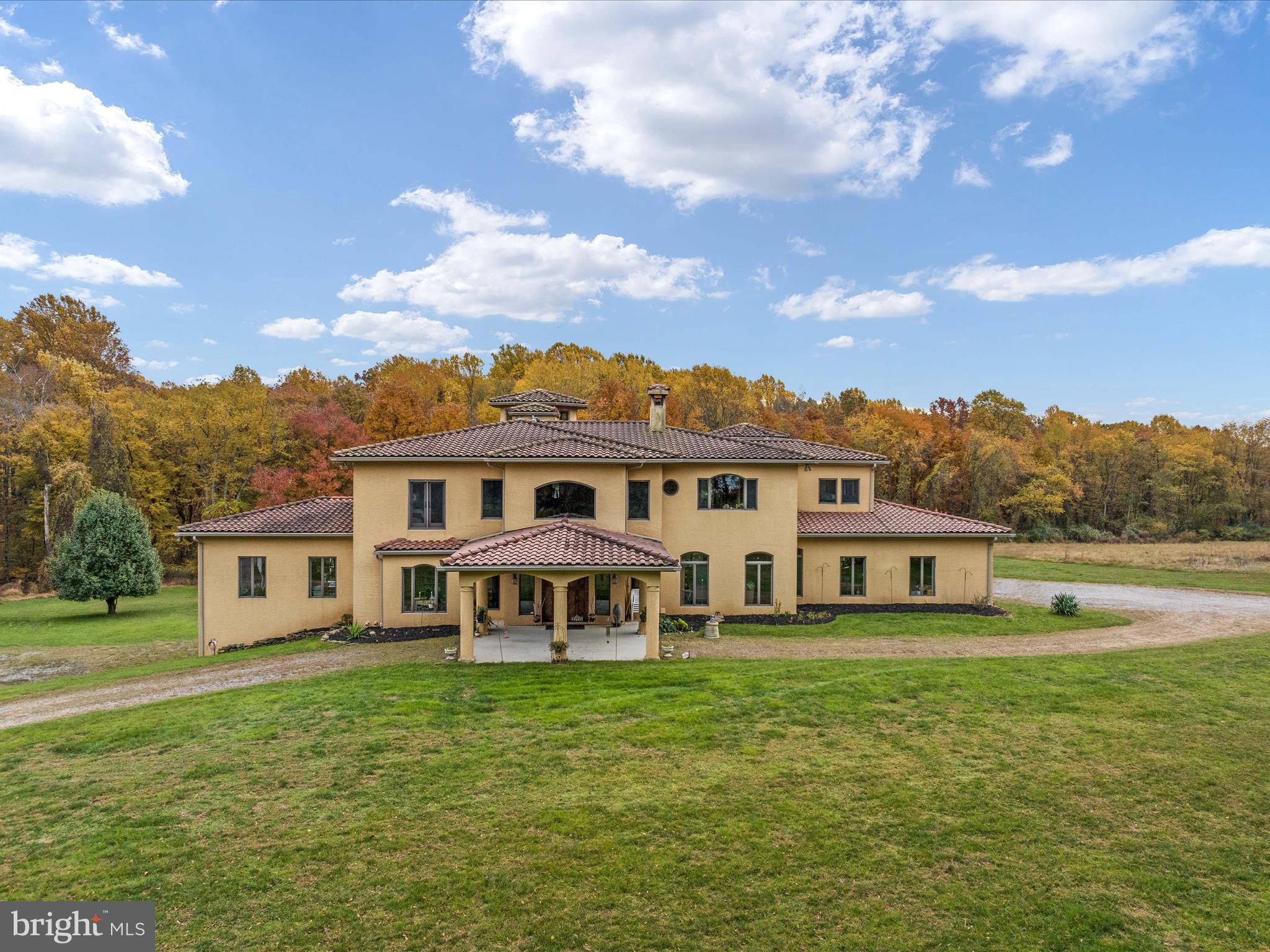 Nestled within a sprawling 41-acre estate, this one-of-a-kind Spanish-style residence at 2705 Deer Park Road is the epitome of luxury and exclusivity in Finksburg, Maryland. A quarter-mile driveway leads you into a world of elegance, surrounded by approximately 17 acres of lush trees, creating a private and serene oasis. The architectural brilliance of this home is evident in its authentic Southwest design, featuring a stunning terracotta-tiled roof, arched windows, and interiors adorned with Ponderosa Pine beams. Every detail, from the southwest doors imported from Albuquerque to the double curved birch stairway in the foyer complemented by handmade iron railings, exudes sophistication and style. The home boasts high 9+ foot ceilings, a fully finished basement, and unique design elements like rounded corner beads and flat arches. Experience tranquility and comfort with super-insulated concrete exterior walls, ensuring a peaceful living space. The meticulous attention to sound and temperature control is evident in the insulated interior floors and walls, along with radiant floor heating powered by Geothermal HVAC units. Large floor-to-ceiling windows flood the space with natural light, while the property's utilities are top-notch, including a 12rpm well, high-speed cable wiring, and a 1000-gallon owned in-ground propane tank. The 1500-gallon private septic tank, tankless propane-fired water heater, and high-powered Thermador wok/cooktop burner add to the home's modern conveniences. Luxury extends to the home's three fireplaces, including two gas (one double-sided) and one wood-burning. The bathrooms are a haven of relaxation with a steam shower, jetted tub, and Roman walk-in showers. An elevator shaft is ready to connect all three levels, and a unique lookout space offers panoramic views of the estate. This property is not just a home but an opportunity to indulge in grandeur and sophistication. It also comes with the added advantage of an agricultural tax benefit, transferable to the new owners. 2705 Deer Park Road is more than a residence; it's a statement of unparalleled luxury.