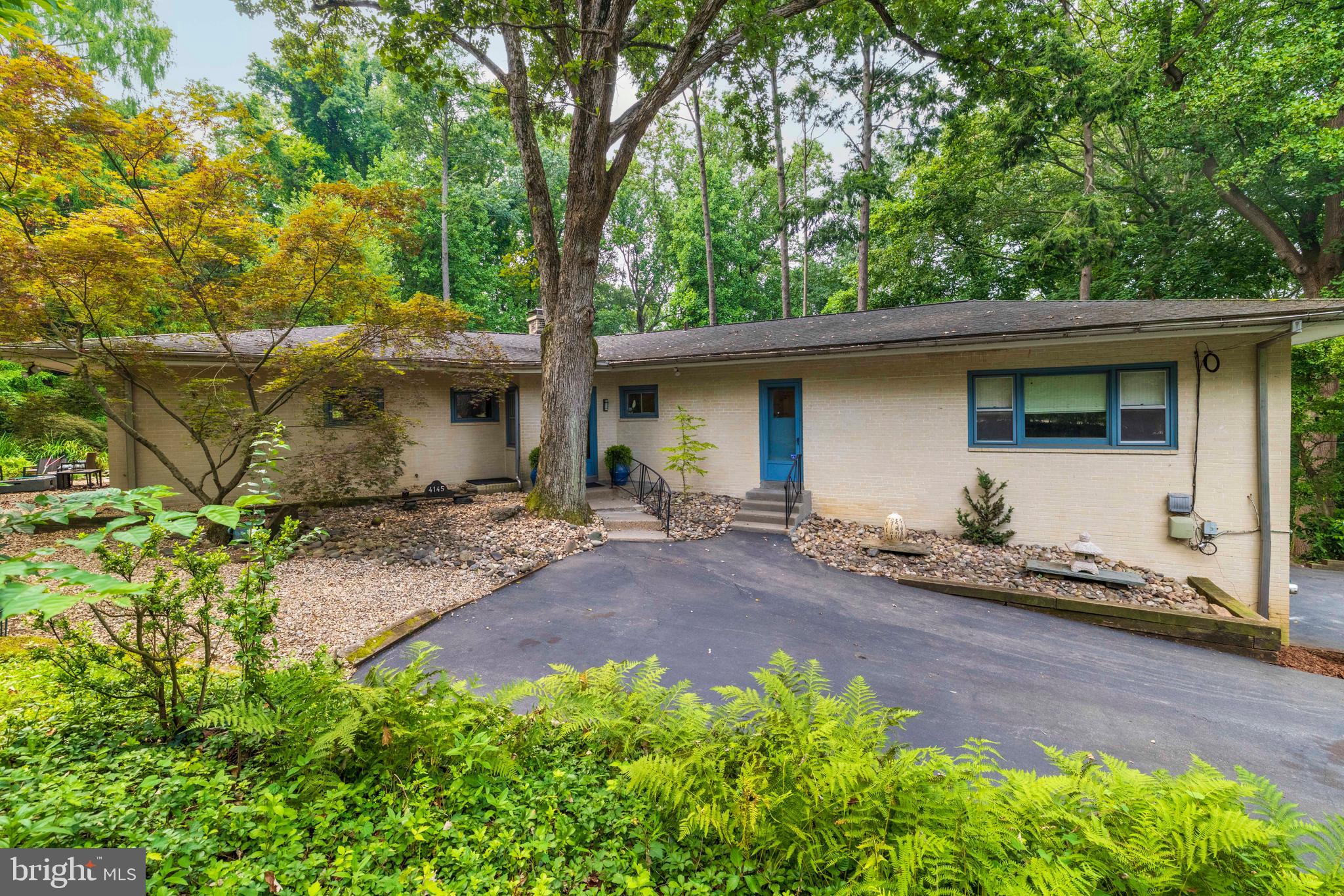 4145 Timber Lane is a mid century modern gem nestled in a bucolic setting  on one of the area's premier private lanes. Built in 1956 the expansive residence was designed by prominent Philadelphia architect  Norman Cronheim.  In his career Cronheim worked with other noted Philadelphia modernist architects including the famed Louis Kahn and architect Oscar Stonorov who designed several nearby dwellings . Travel almost to the end of Timber Lane, leaving the world behind, and buyers will find 4145 behind privacy fencing. The exterior of the home is straightforward and welcoming with hints that the grounds should be explored. Inside the home radiates light and space. The main level of the home offers complete one story living with a finished lower level with its own entrance. Rooms on the main level are large and well proportioned with windows bringing the outside in. The living room is exceptional with its fireplace and wall of built ins as is the primary bedroom.  Rest in this room and hear the soothing sounds of the waterfall outside emptying into the koi pond. There are three additional good size bedrooms on this level and three full bathrooms including the huge primary bathroom with adjoining walk in closet. The  kitchen is bright and airy with extensive counters and ample cabinetry. The pristine Thermador wall oven and cooktop offer vintage appeal.  An angled wall creates breakfast space and adds design interest. Hallways are lined with closets, another midcentury touch. The lower level of the home includes an additional bedroom, full bathroom, kitchen , sitting area, laundry room and storage. The home opens beautifully to the exquisite outdoor space. The lot is just shy of an acre with lovely woods, meadows, peaceful sitting areas. Nature can be enjoyed to its fullest.  Patios and hardscaping allow for outdoor dining and entertaining. This home is in great shape. The air conditioning system is brand new and the roof is recent. There is a  2-car garage and driveway parking for additional cars. 4145 Timber Lane may be situated in one of the greenest and most private areas of the city but it is a stone's throw to Kelly Drive, I-76 and other important arteries to city areas and the suburbs. Center City is just 15 minutes away. Come see!