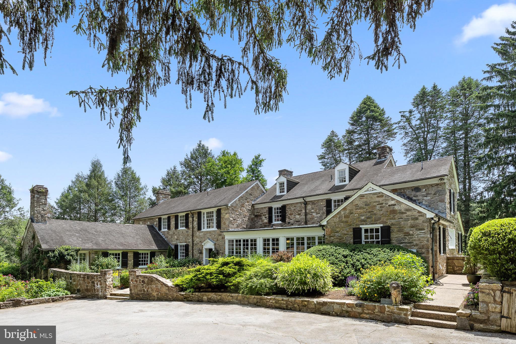 An extraordinary 26+ acre legacy estate set atop a serene hillside just outside West Chester, offered for the first time in nearly a quarter century and located within the nationally acclaimed Unionville–Chadds Ford School District. This remarkable Chester County compound is a masterclass in timeless elegance, defined by breathtaking stonework and an unrivaled sense of place. A private, tree-lined approach unfolds along a picturesque stream, revealing a grand arrival experience as you pass the enchanting pool house and arrive at the majestic stone farmhouse. The estate spans three parcels and includes an approximately 8-acre vineyard producing award-winning Cabernet Franc, Grüner Veltliner, and Albariño—offering both beauty and prestige for the discerning vintner or collector. Rooted in history yet refined for modern luxury, the original 1800s farmhouse—expanded in the 1920s and 1970s—has been meticulously reimagined. Thoughtful renovations elevate every space, including a chef’s kitchen, bespoke bathrooms, and exquisitely restored auxiliary buildings. The main residence is a private sanctuary featuring 5 bedrooms and 4.5 baths, where old-world craftsmanship meets sophisticated comfort. A dramatic entrance framed by stone walls and curated gardens with a tranquil koi pond leads to a gracious center hall and opens to sweeping terraces with panoramic views of rolling meadows and protected woodlands. Inside, exposed stone, artisan millwork, and multiple fireplaces create an ambiance of understated grandeur. The gourmet kitchen is both functional and stunning, with a sunlit breakfast area, butler’s pantry, and seamless flow to an elegant dining room and outdoor entertaining spaces. A refined living room with marble fireplace and custom built-ins, along with a richly appointed office, den, and mudroom, complete the main level. The upper level hosts a luxurious primary suite with sitting room and spa-inspired bath, along with additional beautifully appointed bedrooms. Beyond the main house, the estate unfolds into a collection of exceptional lifestyle amenities. A 4,000 sq. ft. guest house offers sophisticated accommodations or executive-level workspace. The fully reimagined pool house is a destination unto itself, featuring a lofted bedroom, full kitchen, designer bath, and striking stone fireplace—perfectly positioned beside the resort-style pool, surrounded by manicured hydrangeas and elegant stonework. A truly rare offering, the converted stable has been transformed into a world-class art studio, thoughtfully designed for creative pursuits across multiple disciplines, including woodworking, ceramics, painting, and photography. Flooded with natural light and opening to a stone terrace overlooking the vineyard, it is both inspiring and functional. Completing the estate is a newly constructed four-car garage and the inherent flexibility of three separate parcels, offering future possibilities for expansion, equestrian pursuits, or continued vineyard operations. Ideally situated near Longwood Gardens with effortless access to Philadelphia, Wilmington, and the charming borough of West Chester, this exceptional property represents a once-in-a-generation opportunity to own a private countryside estate of rare distinction, beauty, and legacy.