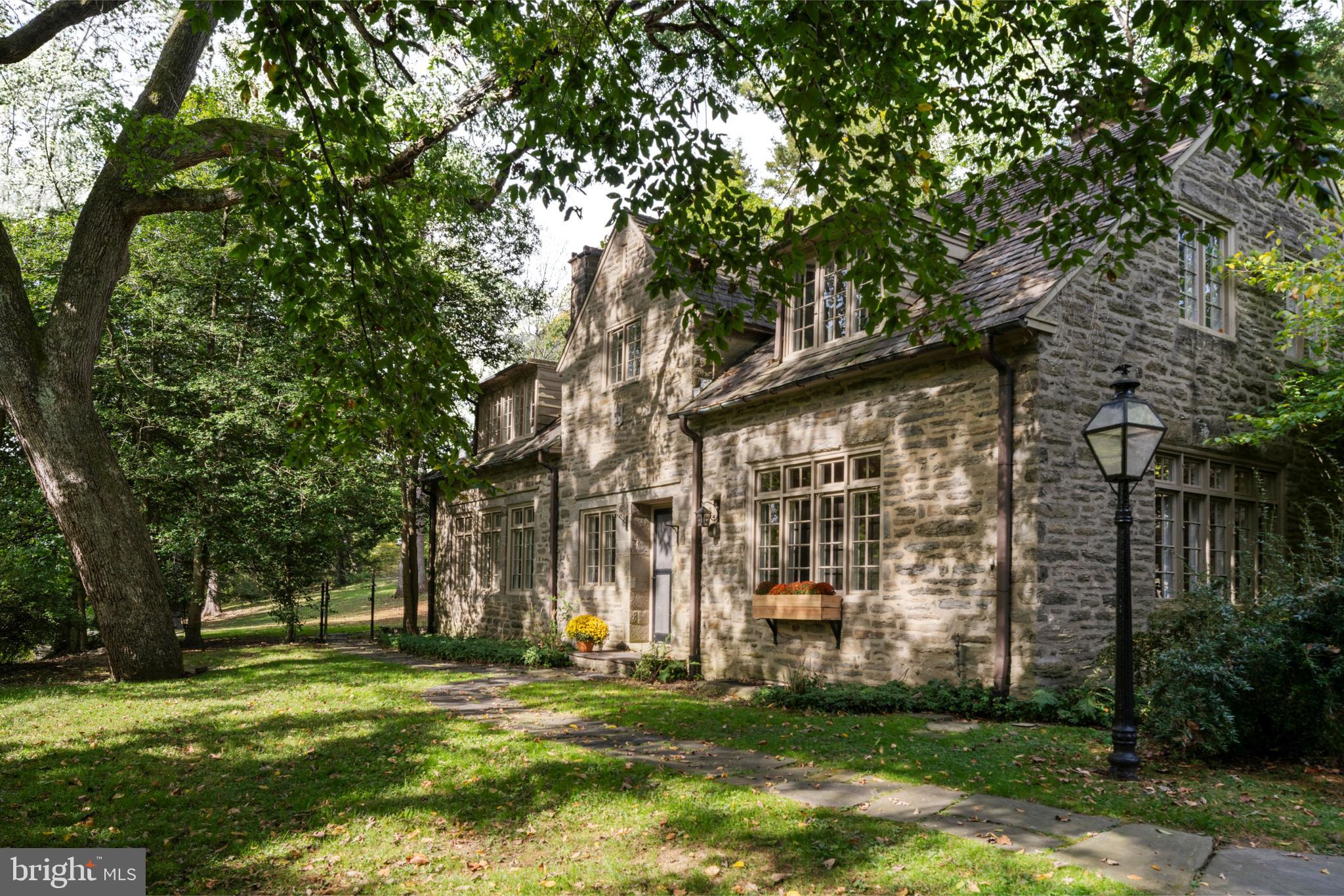 Discover an extraordinary living experience in the heart of Chestnut Hill with The Last House, an architecturally significant stone residence designed in 1894 by Mantle Fielding in 1894. Originally part of the grand Norwood Hall estate, this Colonial Revival home exemplifies Chestnut Hill’s storied architectural heritage—where elegant design, craftsmanship, and history converge on one of the neighborhood’s most distinguished enclaves.

Perched high above the Wissahickon Valley on nearly 2 acres of beautifully wooded grounds, the perfectly sized property offers over 3,700 square feet of light filled living space across two thoughtfully designed levels. Drawing inspiration from French and Colonial influences, The Last House showcases custom mill work, hardwood floors, soaring ceilings, and two heart warming fireplaces that enhance its timeless elegance.

Upon entry, the welcoming foyer leads seamlessly into a sophisticated living area highlighted by a stone fireplace and French doors that open to a blue stone terrace and the expansive grounds. The formal dining room is complemented by two large built-ins, providing both charm and functionality. The spacious kitchen is perfect for entertaining and is equipped with a double oven, marble countertops and ample cabinetry, all overlooking a gated patio. Adjacent is a well-appointed butlers pantry complete with laundry area, wine refrigerator and an abundance of built-in storage furniture.

The first level also houses a versatile side room with a closet and a full bathroom —ideal as an additional bedroom for first floor living. Sliding doors lead to a slate pathway that meanders through the serene landscape. An additional library on this level provides an excellent home study or sitting area, and a conveniently located half bath completes the main floor.

Ascend the elegant staircase to the second floor, where four bedrooms and three full baths await, including a luxurious primary suite with a private fireplace. Two of the bedrooms meet at adjoining the full bathroom with separate tub and shower, ensuring comfort and privacy for family and guests.

The finished lower level boasts a bar area for entertaining, pine walls,  slate flooring, ample storage space for a workshop and a walk-out to the side driveway area.

The outdoor space is truly special, featuring a heated pool adorned with an ornate wrought iron fence, pool house, and numerous sitting areas perfect for enjoying panoramic views of the sunrise and sunset. There as a unique greenhouse that is storied to be designed renowned architect Louis Kahn. Additional amenities include a water filtration system, a second staircase leading from the kitchen to the upper level, a two-car attached garage and driveway parking for up to ten vehicles.

Located along one of Chestnut Hill's most architecturally distinguished stretches, The Last House reflects the legacy of the Norwood Hall estate and the work of prominent Philadelphia architectsTheir influence defined the neighborhood’s early residential character, blending classic design seamlessly with the beauty of the surrounding landscape. Today, that tradition endures—offering a rare opportunity to own a piece of history in Philadelphia’s garden district, where timeless architecture and modern comfort live in perfect harmony. Come make yourself at home at The Last House at the end of the road.