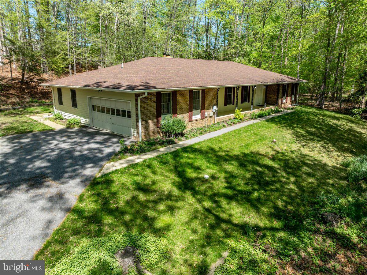 In the heart of Davidsonville’s coveted Harbor Hills, where wooded slopes cradle the edge of the South River, a rare opportunity presents itself.

Set back on a private drive and spanning just over 1.3 acres, this alluring 4-bedroom, 3-bath home offers a harmonious blend of natural serenity and thoughtful design. The versatile fourth bedroom—complete with its own sink, dishwasher, and countertop—lends itself effortlessly to an in-law suite, guest quarters, or creative studio retreat.

The kitchen is built for everyday living, with plenty of cabinet space to keep things organized and stainless steel appliances that are durable, modern, and attractive. It’s a comfortable space that works just as well for weeknight dinners as it does for weekend get-togethers. It opens up to a roomy living area overlooking the front yard that changes beautifully with the seasons.

Surrounded by nature at every turn, the home’s layout invites both quiet reflection and connection. A generous front yard, framed by towering trees, sets the stage for peaceful mornings and lively gatherings alike. The All Seasons Room beckons you to take in panoramic woodland views year-round, while a fireplace brings warmth and comfort indoors. Beneath it all, a spacious, partially framed unfinished basement awaits your personal touch.

Balancing its tranquil setting with everyday comfort, the home also features a two-car garage and an expansive driveway, accommodating 8–10 vehicles—an uncommon convenience in such a private location.

Life in Harbor Hills flows with the soothing rhythm of the river and the gentle rustle of leaves. Time seems to slow, allowing each day to unfold with a welcoming ease. Within this serene backdrop lies a vibrant, close-knit community where amenities abound: a sparkling pool, tennis and pickleball courts, a newly renovated waterfront clubhouse, a sandy beach with pavilion, playgrounds, ballfields, and a marina for those drawn to the water.

With just 185 homes nestled gently into the landscape, this premier waterfront enclave provides timeless charm, graceful elegance, and a true sense of seclusion. A hidden gem—off the beaten path—ready to welcome you home.