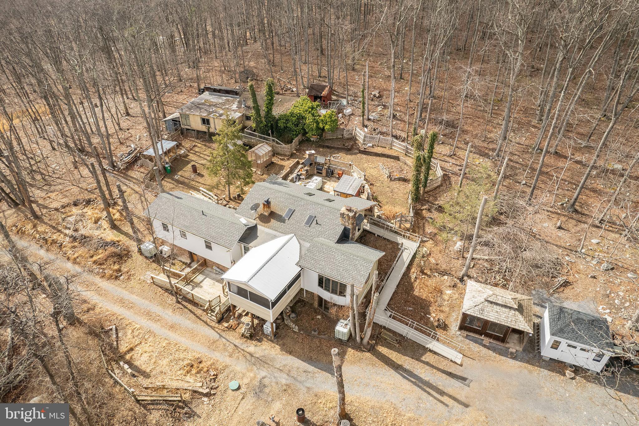 CASH ONLY, PLEASE. ONLY HEAT SOURCE IS THE WOOD STOVE. 
ONLY A PORTABLE COOK TOP FOR COOKING . ABAONDONED BUILDING NEEDS REMOVED IN THE BACK.
Nestled on 6 private acres, this charming home offers a peaceful retreat surrounded by nature, mature trees, and abundant wildlife. While the property needs some TLC, it presents an incredible opportunity for those seeking seclusion and a personal touch. The home features a woodstove for warmth, creating a cozy and inviting atmosphere. Concrete floors and a concrete sink add to the rustic character, providing a unique, low-maintenance aesthetic. First Choice Septic pumped and installed new pipe and a riser, replaced distribution box & conveyance line. 

Though there is no air conditioning, the serene outdoor surroundings and the privacy this property affords will make you feel miles away from the hustle and bustle. Most items, both inside and outside the home, convey, allowing you to move in and make this space truly your own. Whether you're looking to restore it to its full potential or create a custom haven, this home offers the perfect blend of tranquility and opportunity. Pipes have been replaced.  Fridge and Washing machine approx 2 yrs old. The septic has been pumped and repaired recently. The roof is approximately 2 years old.  
2 Green greenhouses, 3 sheds, and a sauna space conveys! 
The old house in the back is uninhabitable.