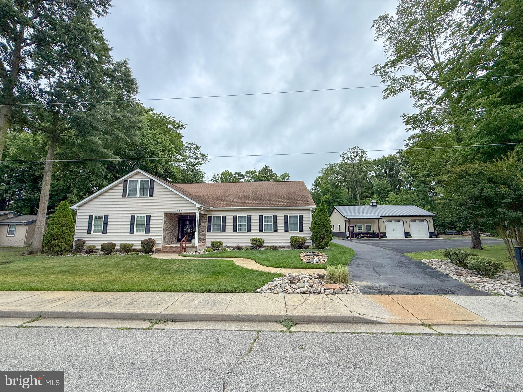 Welcome to this spacious 6-bedroom, 4.5-bathroom home in Delmar, DE, offering approximately 4,300 square feet of living space and room for everyone to spread out. Step inside to find a well-designed floor plan featuring a formal dining room and a large living room highlighted by a brick fireplace. The oversized kitchen is the heart of the home, complete with ample cabinet space, a large center island, granite countertops, tile backsplash, stainless steel appliances, cooktop, wall ovens, and a sliding glass door leading to the covered rear porch. The first floor features a primary suite, along with three additional bedrooms that share a full bathroom, plus a convenient half bath for guests. Upstairs, you'll find a second expansive primary suite with a walk-in tile shower, as well as an additional bedroom with its own full bathroom, providing excellent space for extended family, guests, or multi-generational living. Enjoy outdoor living from the covered porch overlooking the paver patio and impressive stone outdoor fireplace, creating the perfect setting for entertaining or relaxing year-round. Additional highlights include a paved driveway and an oversized pole building with two garage doors, offering exceptional storage, workshop space, or room for hobbies and equipment. This property combines generous living space, functional amenities, and outdoor features in a desirable Delmar location.