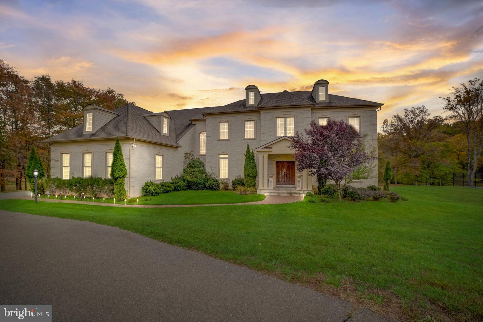 Set on 5 private acres within an enclave of just four homes, this custom-built estate offers over 10,500 square feet of thoughtfully designed living space with 5 bedrooms, 5 full baths, 2 half baths, and a 3-car garage. Graciously set back from the road and framed by mature trees and manicured grounds, the property delivers privacy, scale, and high-level design in equal measure. Inside, dramatic ceiling heights, custom millwork, and abundant natural light define spaces that work equally well for quiet daily living and large-scale entertaining. The gourmet kitchen is anchored by dual marble and walnut islands and equipped with Thermador, Viking, and Sub-Zero appliances, custom cabinetry, and extensive built-in storage — opening naturally to dining and living areas that connect to the outdoor terrace. A paneled library and a private office with terrace views round out the main level. The upper-level primary suite is a genuine retreat — sitting area, fireplace, custom dressing room, and a spa-style bath with walk-in shower and makeup vanity. Secondary bedrooms are generously proportioned with well-appointed bath access throughout. The lower level is built for both recreation and refinement: a private cinema with Stewart screen and 11.2-channel surround sound readiness, a dedicated fitness room, and an oversized wine cellar with brick and wood detailing. Smart-home infrastructure runs throughout — integrated audio, automated lighting and window treatments, video surveillance, and CAT-6 wiring. Outside, an expansive patio and full outdoor kitchen — grill, sink, refrigerator, dishwasher, and volcanic stone bar — anchor a park-like backyard bordered by a gentle creek. A private tennis court completes the picture, with additional open space offering potential for a future pool, cabana, or equestrian use, subject to applicable approvals.
Few properties at any price point offer this combination of acreage, amenity, and seclusion. Offered by private showing only.