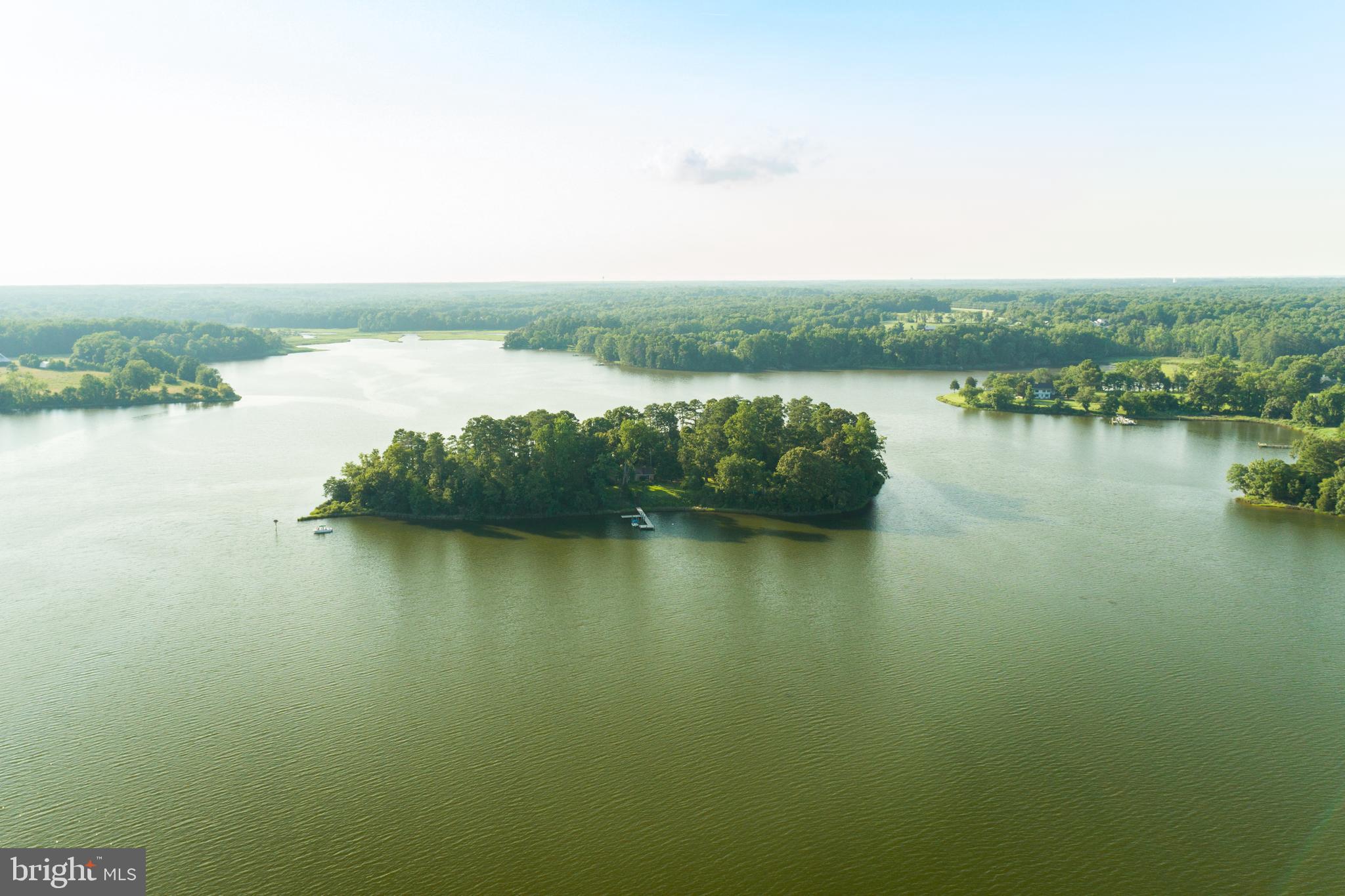 Your Own Private Island; A 90-Minute Drive from Washington DC

Even if our own experience was different, most of us can envision care-free summer days at the shore. Games on the beach, hiking in the forest; only coming back to the house at sunset when it was obvious that we were late for dinner. Now you and your family can create your own summer wonderland with the purchase of an idyllic island located in a sheltered cove of the Chesapeake Bay.

Tippity Wichity Island includes a charming and spacious three-bedroom home with a focus on connection to the lush grounds and surrounding water. Each bedroom provides direct outside access. One side of the home features two bedrooms, one of which is the primary, and a full bath. The primary bedroom provides a prominent view of the St. Mary’s River through sliding glass doors giving way to a private porch. The third bedroom and additional full bath are located on the opposite end of the living area for guest privacy. 
The open “great” room of the home serves as the central gathering place, providing ample space for living, dining, and entertaining. The room is accentuated by a wood-burning fireplace in the center and large windows offering views down the river on one side and access to the back porch, garden, and grounds on the other.  While each of the numerous porches offer a unique view and tranquility, the highlight is the screened-in “gazebo” porch. The space welcomes outdoor dining year-round or a shaded respite with the ebb and flow of the river in the background. 

The Island itself is just under 5 acres highlighted by the dock with boat lift, permitted riprap shoreline and living shoreline with a small beach, soft launch for kayaks/canoes, scenic nature trail and multiple storage structures. The river is clean and temperate, but a heated in-ground swimming pool sits adjacent to the house in its own private garden location.  Although much has been written about the erosion of islands in the Chesapeake, Tippity Wichity sits four meters above the high-water line and is protected from all but the most calamitous storms. Mean low water at the boat dock is approximately six feet, which allows for many sail and powerboat options. 

Nestled squarely in the St. Mary’s River Sanctuary, the Island provides a scenic outpost for nature enthusiasts and the avid outdoorsperson to pursue the abundant wild game and fish down the river, across the mouth of the Potomac, and into the fabled Chesapeake Bay. This incredible property could also serve as a corporate/non-profit retreat or sporting lodge.  The property enjoys an easement across farmland on the bank of the River for access to a dock. In addition, the Island itself is just a 5-10 minute boat ride from St. Mary’s College, an historic liberal arts college in St. Mary’s City. In addition to shopping and dining options, the town/College and nearby Leonardtown offer ample opportunities for entertainment, including an outdoor summer concert series and the Governor’s Cup yacht race.