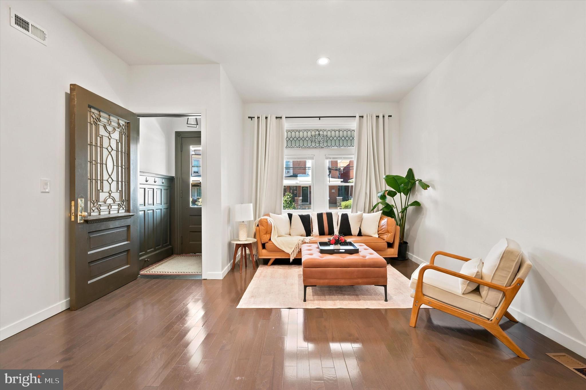 This perfectly sized West Philly twin was elegantly renovated from top to bottom just five years ago and has only been improved upon by the current owners. With soaring ceilings, hardwood flooring, an abundance of windows and a chic greige and white color palette throughout, the home features a layout that is super spacious without being overwhelming. It’s got a wide-open floorplan on the first level with a handsome powder room and an absolute knockout of a kitchen; three bedrooms including a primary suite upstairs; and nearly 900 square feet of additional living space in the finished basement. The kitchen boasts beyond-ample storage space via white Shaker-style cabinets–which the sellers upgraded with a new custom coffee station flanked by pantry cabinets on either side–charcoal granite countertops, a GE appliance package including a five-burner range with griddle insert, and a large island with breakfast bar and Frigidaire wine fridge. The roomy, like-new raised deck provides a seamless transition for indoor/outdoor living and entertaining. Alongside these must-have contemporary updates, the original front leaded glass window; entry door; and vestibule tile, wainscoting and interior leaded glass door were all preserved. Upstairs, the front primary suite with tray ceiling and bay window has a walk-in closet and a luxe en-suite bathroom completely reinvisioned by the homeowners with stylish cement mosaic tile floor and an oversized step-in shower with glass doors, penny tile floor with integrated drain, white full-wall picket tile surround and triple-handle rainfall shower system. The sunny middle and rear bedrooms both have large closets with custom organizers. There’s a convenient upper-floor laundry closet with LG ThinQ frontloaders, and a hall bath with polished porcelain flooring, large vanity, and large-format veined porcelain wall tile that stretches to a full-wall surround for the soaking tub. The finished basement with wood plank tile flooring and five windows runs the full length of the house and has two large storage closets and a door to the rear yard via convenient, weather-fighting Bilco doors. The great Garden Court location has community greenspace nearby, not only at Malcolm X Park but Cedar and Clark parks too. University City is walkable and just a few minutes’ trip away via bike, bus or car, and the best of Baltimore Ave and the 52nd St corridors are at your fingertips as well.