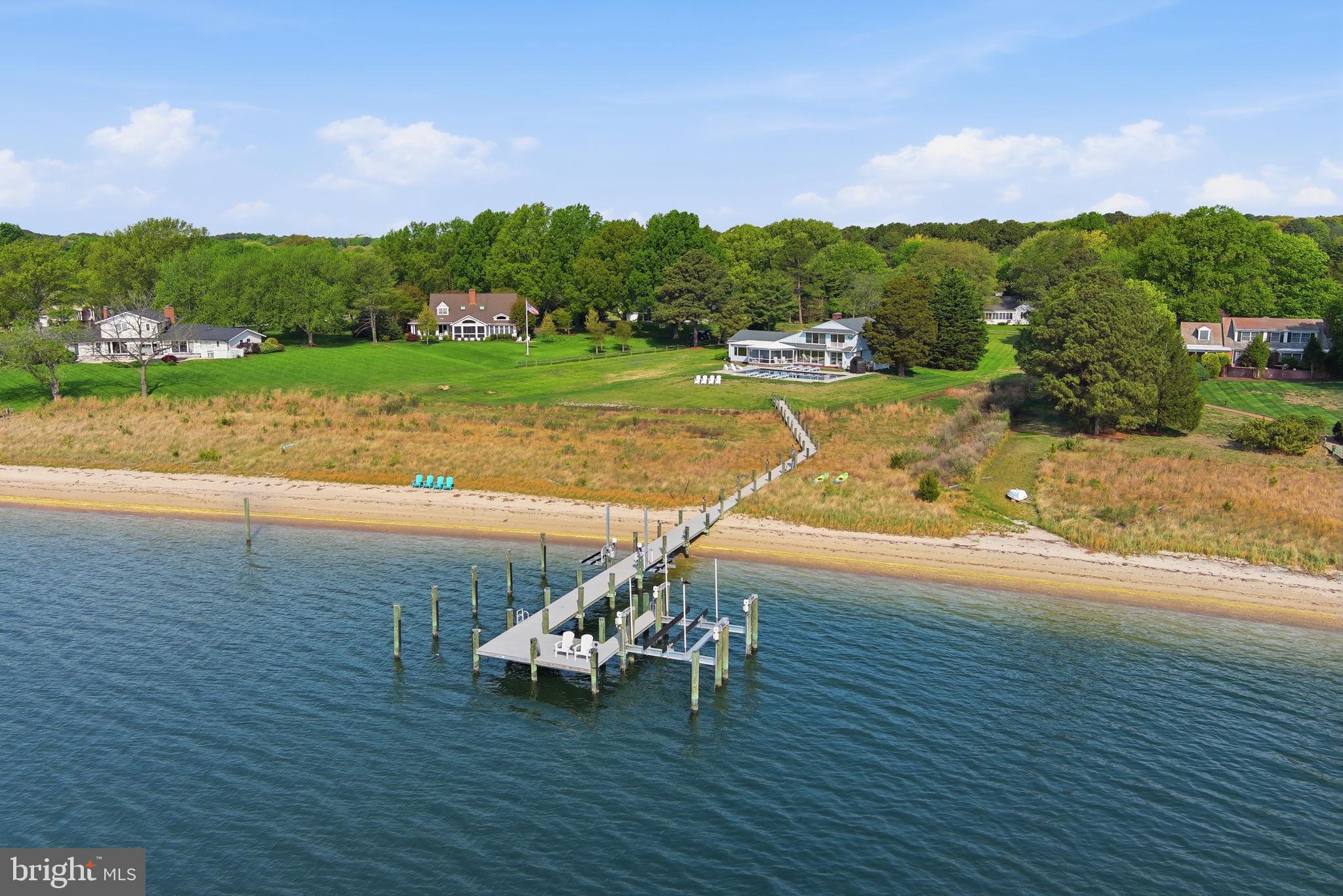 DREAMING OF  A BEACH HOUSE ? STUNNING LOCATION , ENDLESS BREEZES AND SUNSETS.....
A treasure of vantage points and chic contemporary beauty, this Martingham waterfront retreat offers rare front-row views of Miles River happenings - including the historic Log Canoe Races, Fourth of July fireworks, daily passages of billowing sails,and, on crisp days, sightlines stretching for miles. 
Set on 2.32 acres with nearly 250 feet of sandy shoreline, life here moves with effortless rhythm; from morning beachfront strolls to afternoons shaped by regattas, summer pool partiesand in-town finds. Relax by the   awe inspiring extra large 50 foot  heated pool with jacuzzi with of space for sunbathing and relaxing. There is also a IGLUCRAFT sauna from Eastonia for the health concious resident.
Within your home of contemporary coastal personality, 2,875 square feet are serene and elevated as walls
of airy hues allow gridless-windows to compose ever-changing artwork of golden sunsets, lifting fog, and distant gliding hulls.
Built-ins display collected shells and photographs from travels, while a glowing hearth anchors conversation with holiday guests. Spend unhurried Sundays in the landscaped-wrapped screened-in porch. Here, dream-up recipes for the weekend’s gatherings, while the kitchen’s updated stone surfaces and appliances prepare everything from perfect picnics to generous crab feasts. At day’s end, two and a half modern baths soothe, partnering with a main-level primary suite and two additional bedrooms—including airy loft. serving as a 4th bedroom. From your 125-foot pier with 8–10 feet MLW,  welcome the seasonal residents that live on the Osprey platform, launch kayaks toward the picturesque edges of Long Haul Creek or set sail into the open reaches of the Chesapeake Bay. While on tour, spot sea glass along the shore, linger at the pier, and imagine the ease of your two-car garage.
The dock - built by WHEEMS - offers 2 jet ski lifts, a 16K pound boatlift, electric and water and a platform area to sit over the water and relax .
 From home, St. Michaels charms just minutes away, where beloved shops, dining, and harbor life fill easy afternoons, while rounds at The Links at Perry Cabin, cycling routes, and scenic trails shape the days between.
The roof has been replaced by MARASUN in 2022, new HVAC in 2021, pool build in 2022, new water heater 2023.