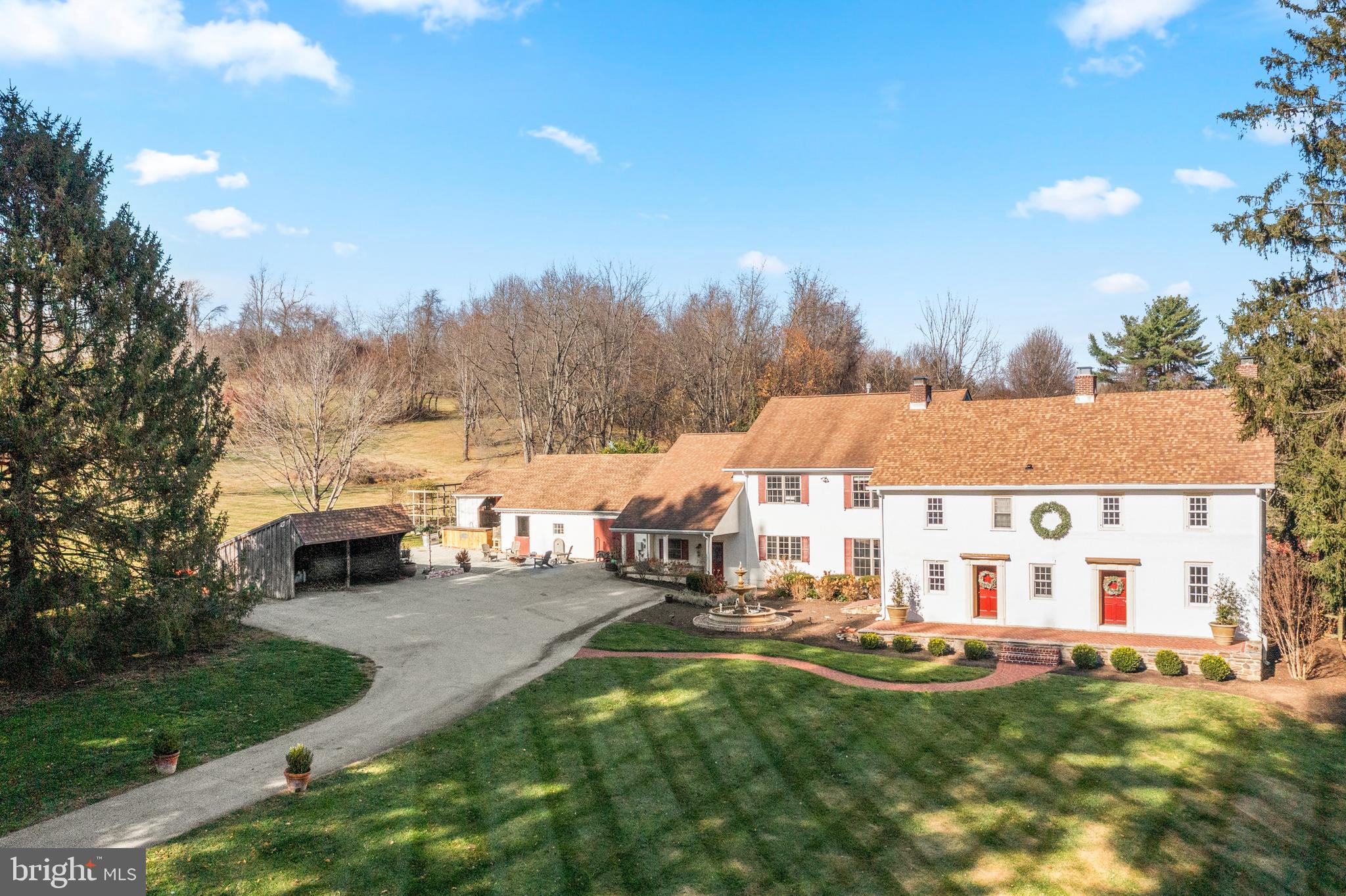Experience timeless elegance with this stately Chester County farmhouse nestled on over 4.6 acres within the coveted Unionville-Chadds Ford School District. A gated entrance leads you to a classic 1746 stone farmhouse seamlessly enhanced by a 2009 addition, combining historic charm with modern luxury. The original stone farmhouse welcomes you with two distinct entrances: one opening into a living room adorned with deep marble windowsills and a cozy wood-burning fireplace, and the other into an inviting den featuring a brick-surround wood-burning fireplace and a convenient half bath. Adjacent to the den, discover a rustic pub boasting exposed stone walls, a fireplace, a bar, and direct access to a rear patio overlooking perennial tiered gardens, a tranquil fountain, and a sparkling pool—your private oasis. Upstairs, three spacious bedrooms offer scenic countryside views, complemented by a full bath and a large laundry area. The 2009 addition greets you with a charming front porch leading into a front-to-back mudroom, a generous pantry, and a half bath. From here, step out to a patio surrounded by perennial gardens and the inviting inground pool. The mudroom connects to a hallway featuring a full bath and an additional bedroom, flowing into an expansive great room and gourmet kitchen. This space is highlighted by a wood-burning stove, exposed beams, and a striking stone wall. The kitchen is a chef’s dream, equipped with a large island perfect for entertaining, a soapstone farmhouse sink, a 6-burner gas Wolf cooktop, double ovens, a Sub-Zero refrigerator, and two dishwashers. Enjoy casual meals in the cozy breakfast area with stone walls and serene views of the fountain and manicured lawn. The formal dining room in the original section of the house offers an elegant setting for special occasions. Ascend the stairs from the great room to the luxurious primary bedroom suite, complete with a spacious bath, walk-in closet, a sitting area with a gas fireplace, and a private office. A connecting hall with ample closets links back to the stone farmhouse. Outside, the meticulously maintained perennial gardens bloom year-round, complemented by fountains, a pool, a play area, and expansive open spaces for year-round enjoyment. This distinguished farmhouse sits on 4.6 acres offered in its entirety, including two tax parcels. The main house occupies 2.33 acres, while an additional 2.29-acre buildable lot borders 8 acres of open space, presenting exceptional investment potential.