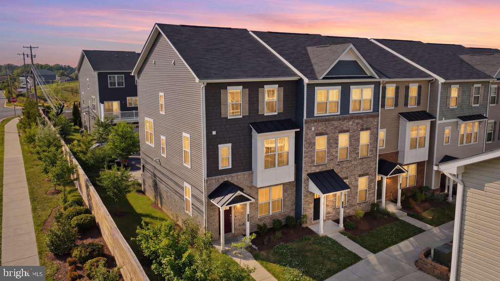 Nestled within Ellicott City’s highly sought-after community of Long Gate Overlook, welcome to 4314 Sheriff Howard Court—an extraordinary Beazer Homes Chesapeake model masterfully designed to deliver elevated luxury living with approximately $175,000 in premium builder and post-settlement upgrades throughout. This spectacular end-of-group residence immediately captivates with its commanding front elevation featuring elegant board and batten siding, rich brick and stone accents, clay-colored shutters, architectural detailing, and a charming covered front porch portico creating timeless curb appeal. Built with lasting quality and efficiency in mind, the home also features a tankless water heater, 35-year architectural shingles, and energy-efficient LED lighting throughout. From the moment you enter the front doors, you are welcomed by a private lower-level bedroom suite complete with its own en-suite half bathroom—perfectly suited for guests, multigenerational living, or a private executive office retreat. Just beyond, a thoughtfully designed command center near the garage entry showcases elegant quartz countertops, rich 42-inch espresso cabinetry, and direct access to the spacious two-car garage and oversized driveway. Ascending the white oak staircase, the main living level unfolds into a breathtaking entertainer’s dream wrapped in walls of windows exclusive to this premium end-unit placement, flooding the home with natural light from every angle. Luxury vinyl plank flooring spans ALL levels with absolutely NO CARPET throughout, while upgraded chandeliers, recessed lighting, and designer pendant lighting elevate every space. At the heart of the home lies the gourmet gas-powered chef’s kitchen impeccably appointed with stunning Carrara Marmi eased-edge quartz countertops, rich 42-inch espresso cabinetry, thoughtfully placed top-of-the-line backsplash selections, premium stainless steel appliances, oversized island seating, and seamless flow into the expansive breakfast nook surrounded by windows galore. Just off the kitchen, a private rear deck offers the perfect setting for elevated outdoor living and entertaining. The expansive dining room is equally impressive—sun-drenched, elegant, and designed for both intimate gatherings and grand-scale hosting—while a beautifully appointed powder room completes the main level. Upstairs, the luxurious owner’s suite offers a true retreat highlighted by dramatic box ceilings, recessed lighting, custom upgraded closet systems, designer window treatments, and a spa-inspired en-suite bath featuring dual vanities, quartz countertops, ceramic tile flooring, an oversized walk-in shower, and a relaxing soaking tub. Two generously sized secondary bedrooms continue the home’s sophisticated aesthetic with luxury vinyl plank flooring, abundant natural light, upgraded window treatments, and access to a beautifully finished secondary full bathroom featuring quartz countertops, ceramic tile flooring, and tub shower combination, while the upper-level laundry area adds everyday convenience. Beyond the exquisite interiors, residents of Long Gate Overlook enjoy premier community amenities including basketball courts, pickleball courts, tennis courts, playgrounds, and beautifully maintained outdoor gathering spaces, all while being moments from Target, premier shopping centers, grocery stores, restaurants, fitness centers like the Y and major commuter routes including Routes 100, 29, and 70 for seamless access to Baltimore, Columbia, and Washington D.C. Zoned to highly sought-after Howard County schools including Centennial High School, Ellicott Mills Middle School, and Veterans Elementary School, this remarkable turnkey luxury residence offers the perfect blend of sophistication, convenience, and lifestyle in one of Howard County’s most coveted communities.