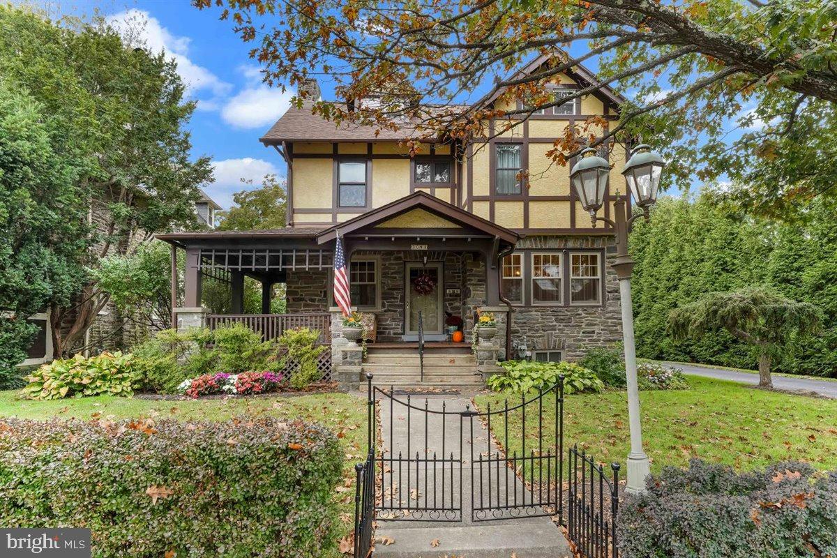 Magnificent English Tudor with open front porch and multiple gardens.  Old World Charm meets Modern Convenience.  The original solid oak front door with new Baldwin Brass Hardware opens into a beautiful living room with a stone fireplace, hardwood floors with inlays and deep window sills.   The dining room (currently being used as a sitting room) has beautiful hardwoods with inlays and deep window sills.  The Great Room accessed from the living room via a pocket door or from the breakfast room, has a cathedral mahogany ceiling, Mt Vernon Pellet stove and a new picture window overlooking the pristine backyard.  The kitchen with Woodmode 42" cabinets, newer appliances (gas cooking), and back stairs from the second floor, leads to the large breakfast room with a new Bay window, a full bathroom with stall shower, the back hall with two large closets and the  delightful partially covered back deck perfect for outdoor grilling.  The second floor houses the primary suite with ensuite bathroom with whirlpool tub, walk in closets and laundry room.  There are 3 additional bedrooms and a hall bath.  All three bathrooms have updated plumbing and fixtures.  Outside there is a private driveway to a two car garage with new garage door and opener and electrical outlet used for a plug-in hybrid vehicle.  Magnificent landscaping surrounds the house on all four sides.   This is a very walkable neighborhood - convenient to all shopping, transportation, Center City, the airport and much more.  The house has been lovingly cared for and updated by the current owner - please see our complete list of all of the upgrades and improvements in the Documents section.