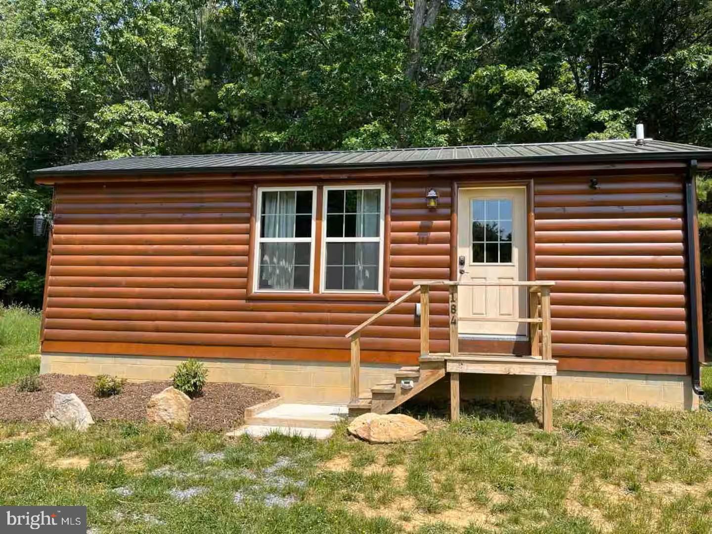 Nestled in a serene mountain setting, this charming cabin-style home offers a unique blend of rustic elegance and modern convenience, making it an ideal investment opportunity. Built in 2021, this detached residence features log siding that beautifully complements its natural surroundings, creating a warm and inviting atmosphere. Step inside to discover an open floor plan that seamlessly combines the kitchen and living area, perfect for entertaining or simply enjoying a cozy evening at home. The interior boasts engineered wood and laminate plank flooring, enhancing the cabin's rustic charm while ensuring durability. The well-appointed kitchenette is equipped with essential appliances, including a front-loading washer and dryer, electric oven/range, microwave, and refrigerator, making it easy to settle in and start enjoying your new space. The home features a thoughtfully designed entry-level bedroom and a full bathroom with a walk-in shower, providing convenience and accessibility. Natural light pours in through the window treatments, creating a bright and airy ambiance throughout the living areas. Outside, the property spans an impressive 6.9 acres, offering ample space for outdoor activities and potential expansion. The lot is cleared and level, with a picturesque pond and lush trees providing a tranquil backdrop. With road frontage and unrestricted zoning, this property presents numerous possibilities for future development or enhancement, making it a savvy investment for those looking to capitalize on the growing demand for rural retreats. The Septic system and electricity are set up for 2 additional one bedroom cabins.  Additional exterior features include a machine shed, providing extra storage or workspace for your projects. There is also a very old 1 bedroom cabin, with no electricity and an outhouse, that can be restored for an additional rental.  The gravel driveway ensures easy access, while the peaceful mountain views and surrounding woods create a serene escape from the hustle and bustle of everyday life. Located in a desirable mountain area, this property not only offers a comfortable living space but also the potential for rental income or long-term appreciation. With its combination of modern amenities and natural beauty, this cabin is a rare find for investors seeking a property that promises both comfort and value. Embrace the opportunity to own a piece of this tranquil paradise, where the charm of cabin living meets the potential for lucrative returns.