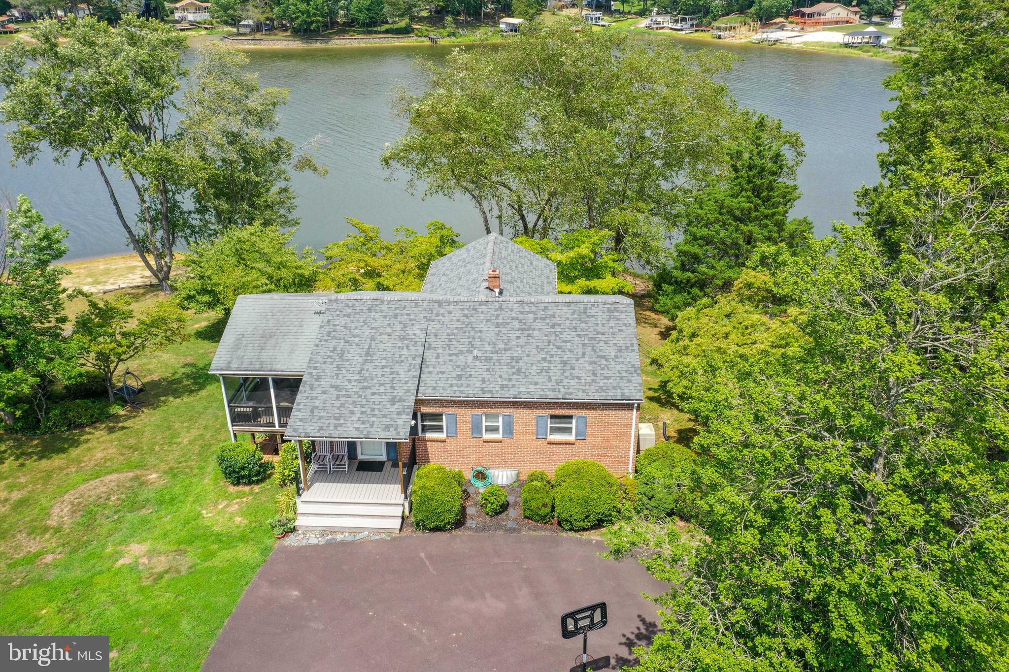 145ft of water frontage in gated Blue Ridge Shores/ Lake Louisa. This charming 2 level brick home, with over 2200 finished sqft, will not disappoint. Set back from the street, this home offers privacy and little traffic noise. A long circular drive leads you to a welcoming front porch and instant water views. This over 3/4 of an acre lot is beautifully landscaped with a variety of trees & multiple lawn areas.  Please note that due to the distance that this home is set back from the lake, flood insurance may not be needed, which is a huge saving! (current owners and previous owners have not been required to pay flood insurance)

Once inside, the home welcomes you with an open floor layout, where the lake views instantly surround your senses in all directions. The stainless-steel appliances, glass backsplash and quartz counters bring a modern touch to the kitchen, which also has a rolling island and opens to a large dining space. The French doors in the dining room lead to one of the best rooms - the large screened-in porch, where you can feel the breeze, hear and see the many bird varieties fly around, while admiring the water view all around. Another amazing room is the light-filled living/sunroom, complete with a wooden vaulted ceiling and floor to ceiling windows, which almost bring the lake inside, while also offering a cozy space for memorable gatherings with friends and family.  

The main level has two lake view bedrooms, both with ceiling fans, good closet space, and sharing a recently renovated modern bathroom. The walkout lower level boasts a good size family room, again with two windows overlooking the lake, two more bedrooms, another recently renovated bathroom, a large utility room and workshop/ storage room (both also overlooking the lake). LVP flooring has been installed downstairs, and beautiful original hardwood flooring can be found upstairs.

Additional Info: Septic Inspection passed in Nov, public water ($122 a quarter), newer roof, front porch, oil heating. Sandy and shallow lake floor; great for swimming and lounging near the property.  Fishing, boating and water sports right off your property! Interior furniture, outdoor furniture, kayak, canoe, paddleboard & household goods included.

This gated community offers 3 beach areas, boat docking space, playgrounds, tennis courts, basketball, hiking trails, on-site management, and year-round community events. Call today for a veiwing!