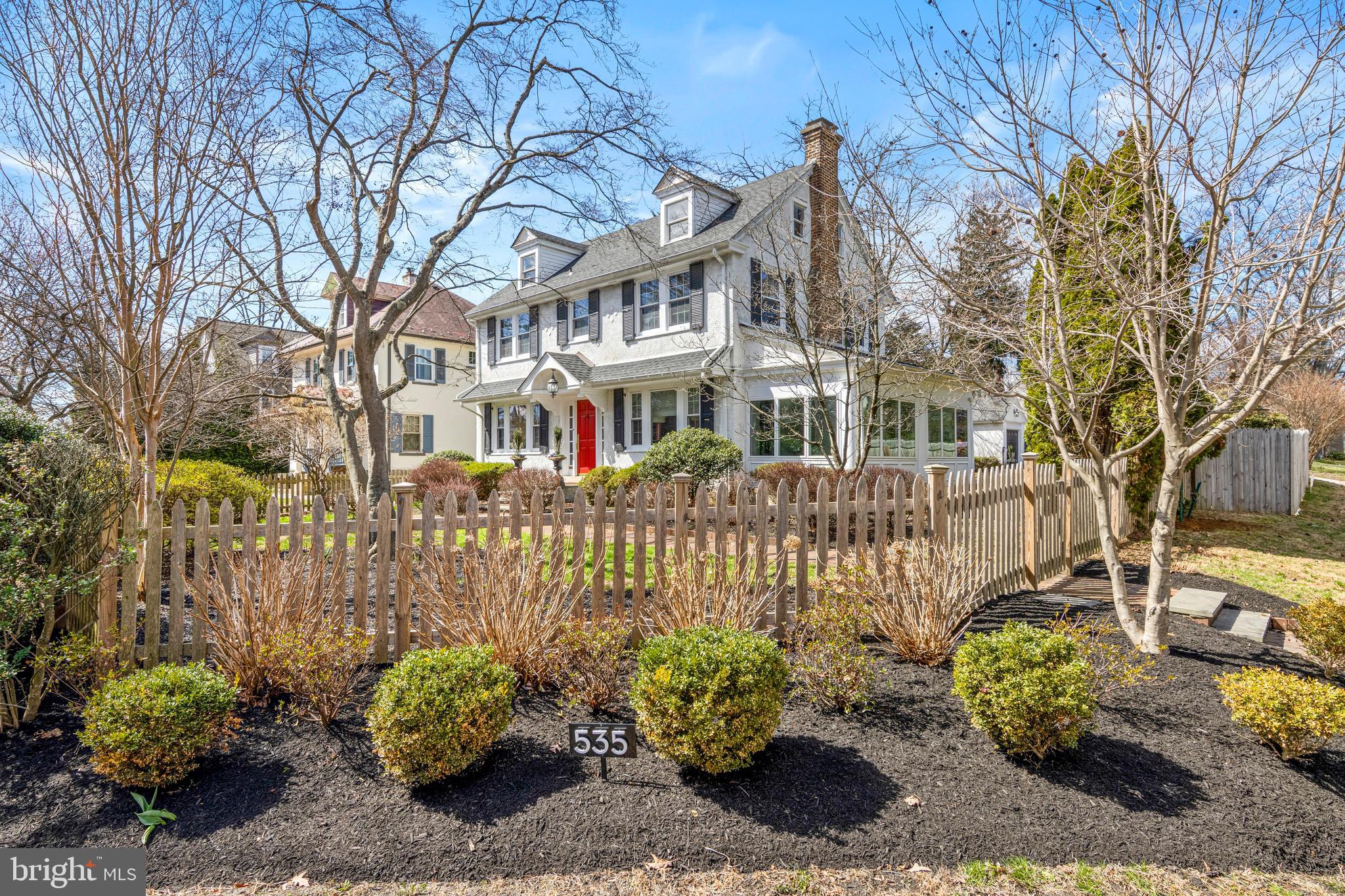 Discover timeless elegance in this four-bedroom storybook Center Hall Colonial in Wyndmoor, gracefully positioned on a fenced in corner lot. Boasting four bedrooms, two full baths, and two half baths, this exceptional home is complemented by a finished lower level and a one-car detached garage. A sunlit foyer greets you with a seamless blend of traditional charm and modern sophistication. Beautiful hardwood flooring, complemented by custom board-and-batten wainscoting and crown molding, adds refined architectural character to this level. Anchored by a striking marble fireplace, the living room offers a warm, inviting space dual glass doors that open seamlessly to the sunroom. Step into the sunroom, where slate tile and abundant natural light create a tranquil setting. The chef-inspired kitchen effortlessly blends style and function, featuring solid wood cabinets, quartzite countertops, a classic subway tile backsplash, and brushed gold hardware and lighting. A raised breakfast bar adds flair for casual dining, flowing into the formal dining room. Modern essentials include a rear mudroom with custom cabinets and a chic powder room that completes this level. The second floor offers a serene primary bedroom complete with sitting area. Two additional generously sized bedrooms are beautifully appointed on this level. Elegantly updated, the hall bath features a glass-enclosed tiled shower, a marble vanity, and modern floral wallpaper. The third floor offers bright, flexible space ideal as two additional bedrooms, a bedroom and sitting area, private office, or a guest suite with a full bath. The finished lower level expands the home’s versatility with space for a media room, recreation area, or home gym. Thoughtfully curated this level includes a laundry room, storage, and an additional powder room. Outside, a private oasis awaits. An oversized bluestone patio sets the stage for unforgettable alfresco dinners, while the fenced backyard ensures privacy. A dedicated fire pit area invites gatherings with friends, creating the perfect blend of relaxation and entertaining. Ideally located just minutes from the shops, cafés, and restaurants of downtown Wyndmoor and nearby Chestnut Hill, this home perfectly balances convenience with lifestyle. With two train lines within walking distance, commuting to the city is effortless.