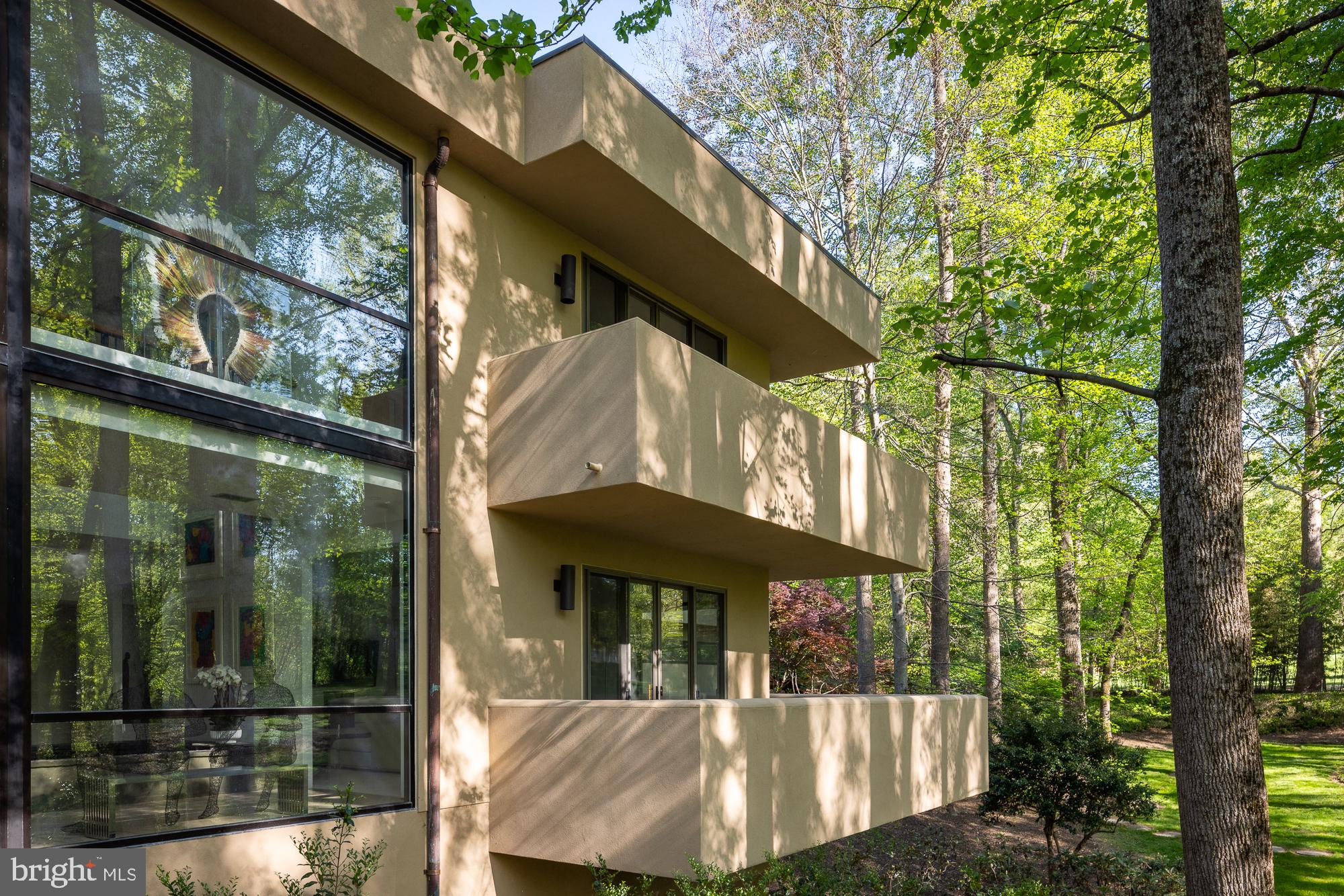 A two story gallery wrapped around an indoor koi pond forms the center of this quietly remarkable residence, where water, light, and movement shape the experience of the home from within.

Concealed within more than eight wooded acres, the approach unfolds gradually through dense trees before the architecture reveals itself, defined by strong horizontal lines, cantilevered forms, and a natural material palette that sits comfortably within the landscape.

Inside, the plan balances openness with clarity, offering a rare combination of architectural intent and everyday livability. Formal living and dining rooms, expansive gathering spaces, a dedicated office, and a well appointed kitchen with adjoining breakfast area are arranged with purpose and ease.

The upper level includes four generous en suite bedrooms, including a guest suite with a striking elevated terrace positioned within the treetops.

Constructed with steel framing and expansive structural glass, the home reflects a level of engineering integrity that supports its architectural ambition. Designed and built by local builder and engineer Jack Wilmore, whose background is rooted in generations of residential design and construction, the house carries a clear sense of authorship and discipline throughout.

Additional features include a three car garage, multiple outdoor terraces, and a setting that offers both privacy and proximity to the Washington metropolitan area.

A distinctive offering for those who value architecture that is considered, enduring, and deeply livable.

A detailed video is available by searching the property address.