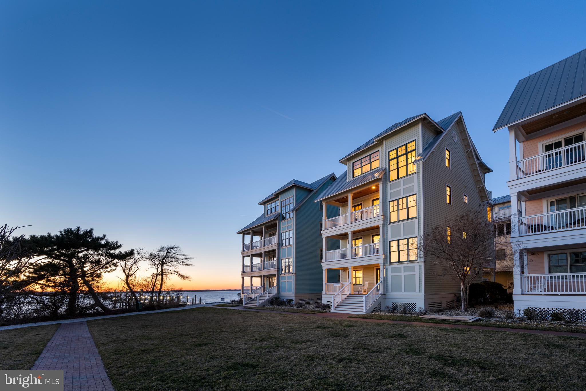 Nestled along the edge of Sunset Island with water views all around, this stunning abode offers a host of luxurious features that awaiting your discovery. Step inside to discover three expansive decks facing southward, offering breathtaking, panoramic vistas of Assawoman Bay. Ideal for entertaining amidst spectacular sunsets, these outdoor spaces provide the perfect backdrop for gatherings. Adding to the allure is the adjacent Mews, a lush open green space ensuring added privacy, with convenient access to a nearby walking trail. Stepping into the home reveals a distinctive Carolina Coastal design, with the kitchen and primary entertaining areas gracefully situated on the third floor. Ascend effortlessly via elevator to a grand foyer flooded with natural light, adorned with soaring 20-foot ceilings. The impressive great room awaits, adorned with a well-appointed kitchen and Butler's pantry featuring top-of-the-line stainless steel appliances, including a gas range, double oven, microwave, and oversize fridge. Adjacent, is an oversized screened room inviting relaxation and cool breezes. Venture to the fourth floor to discover the private owner's suite, complete with it’s own sitting area to relax in or there is plenty of space to have a private office.  Boasting its own secluded deck, it offers even more breathtaking views of the surrounding sunsets and sunrises. Meanwhile, the second floor hosts generously sized kids and guest suites, each complete with walk-in closets and private full baths. Even the practicalities are elegantly addressed, with a laundry area featuring granite countertops, cabinets, and ironing space. The rear two-car garage, along with covered parking for four vehicles, includes an adjoining outdoor shower for added convenience.
Whether entering from the garage or front porch, the lower level offers enormous pleasure and versatility with a den/office or potential sleeping quarters, complemented by a fifth full bath. For more information and to schedule a private viewing of this remarkable residence, please don't hesitate to reach out today.