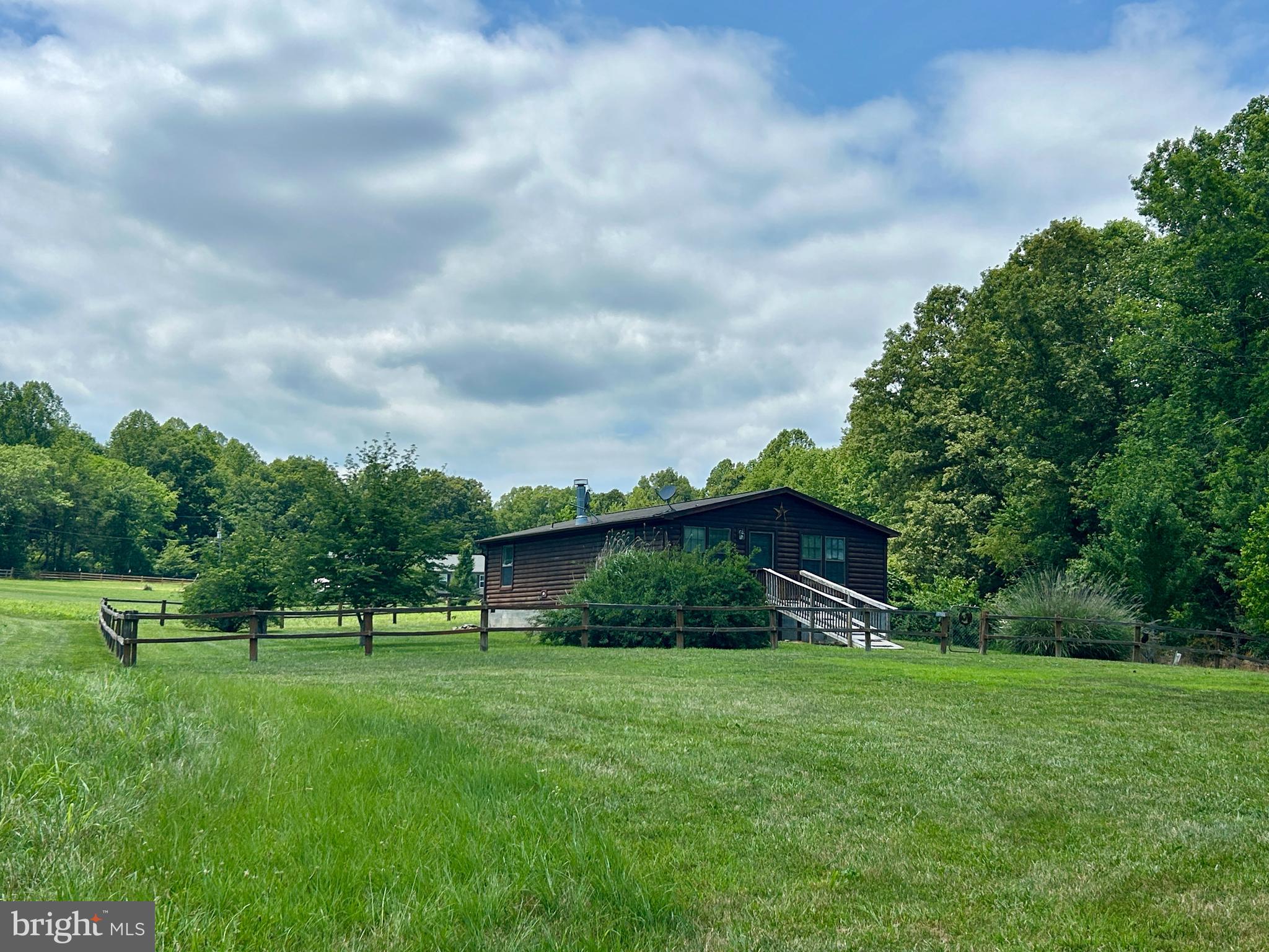 Nestled on 5 peaceful acres, this cedar-sided manufactured home offers privacy, mature landscaping, and plenty of room to enjoy the outdoors. The property is partially fenced and tucked away on a private easement with a shared driveway, creating a quiet, secluded setting. Inside, you'll find a spacious living room featuring a beautiful masonry fireplace, perfect for cozy evenings at home. The bright eat-in kitchen offers an abundance of cabinets and ample space for a dining table, making it ideal for everyday living and entertaining. The home features two generously sized bedrooms, each with walk-in closets, and two full bathrooms. The primary suite includes a private adjoining bath with a walk-in shower. A separate laundry area, abundant closet and storage space, and a well-lit interior add to the home's functionality and comfort. Home is being sold as-is, in good overall condition, but does need a little work.