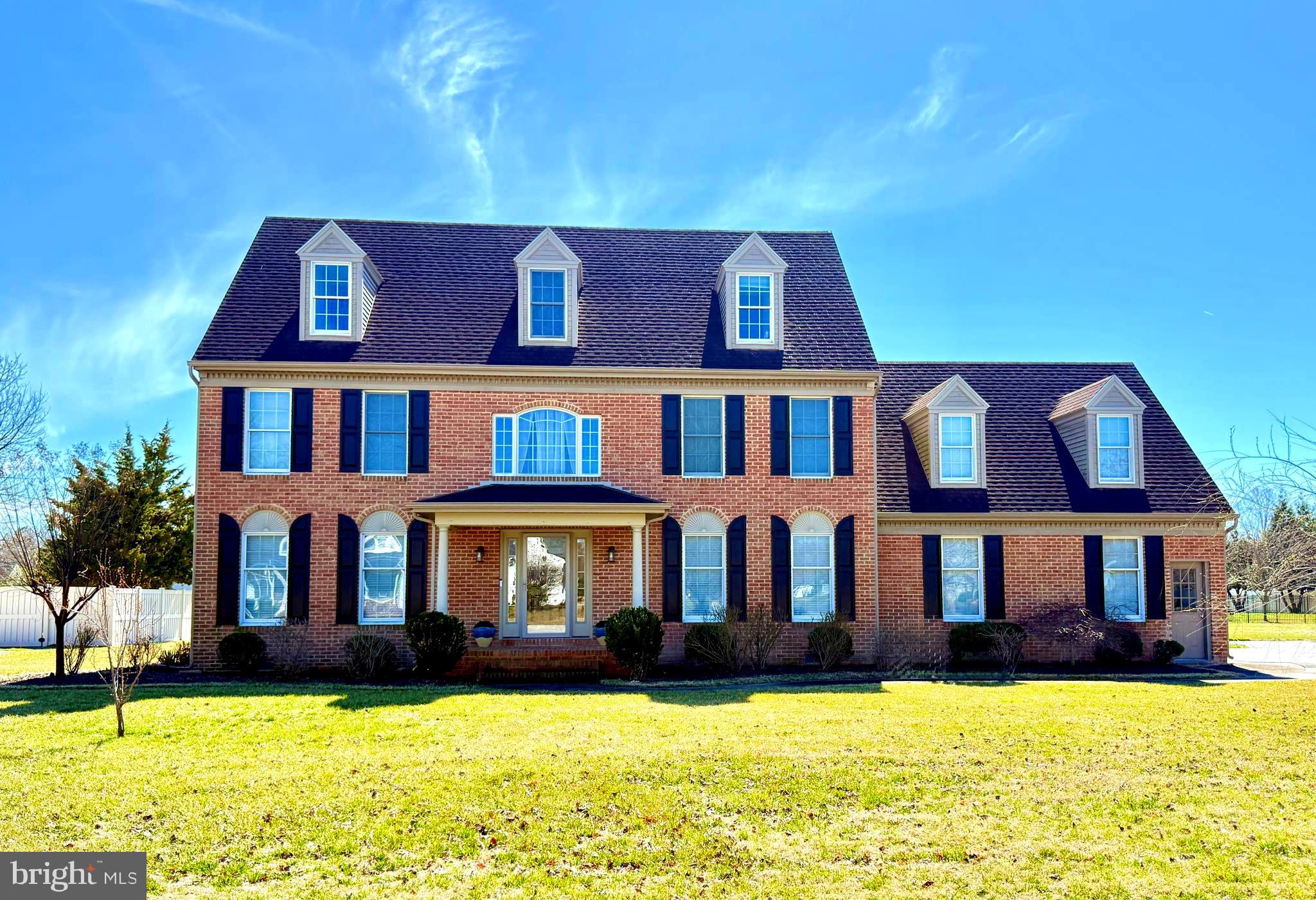 This beautifully maintained 3,178 sq ft brick-front Colonial is located in the desirable Steeplechase community, where residents enjoy amenities including a clubhouse, swimming pool, tennis courts, playgrounds, and scenic ponds.  A curved walkway and covered brick front porch welcome you into the home’s bright two-story foyer. The main level features a formal dining room and comfortable living room, leading into the heart of the home — a spacious kitchen designed for everyday living and entertaining. The kitchen includes white cabinetry, Corian countertops, tile backsplash, a 36" gas cooktop, wall oven, large island, and French-door refrigerator. The kitchen opens to the dining area and inviting family room centered around a gas fireplace with tile surround. Just beyond, a fully finished sunroom with shiplap walls provides additional living space and is heated and cooled with its own mini-split system. Step outside to enjoy a composite deck overlooking a professionally designed backyard retreat featuring a paver patio, fire pit with Breeo smokeless fire system, and landscape lighting—perfect for relaxing or entertaining. Additional first-floor highlights include Pergo hickory flooring throughout the main living areas, a separate laundry room, and a powder room. Upstairs, the primary suite offers a spacious retreat with dual vanities, soaking tub, separate shower, tile flooring, and a walk-in closet. Three additional bedrooms and a full hall bath complete the second level. The third floor provides exceptional flexibility, with two large bonus rooms, each with nearby closets and access to a full bath. These spaces could easily serve as additional bedrooms, offices, fitness rooms, playrooms, or media rooms. Additional features include natural gas heating,  a fireplace, multiple HVAC systems for efficiency, a Rinnai tankless water heater, irrigation system, blacktop driveway, alarm system, and two electrical panels. The attached two-car garage includes a Tesla Wall Connector, making electric vehicle charging easy and convenient right at home.  The finished sunroom is not included in the county tax square footage. This home offers space, flexibility, and thoughtful updates in one of the area’s most sought-after neighborhoods.  Septic is approved for 4 bedrooms.