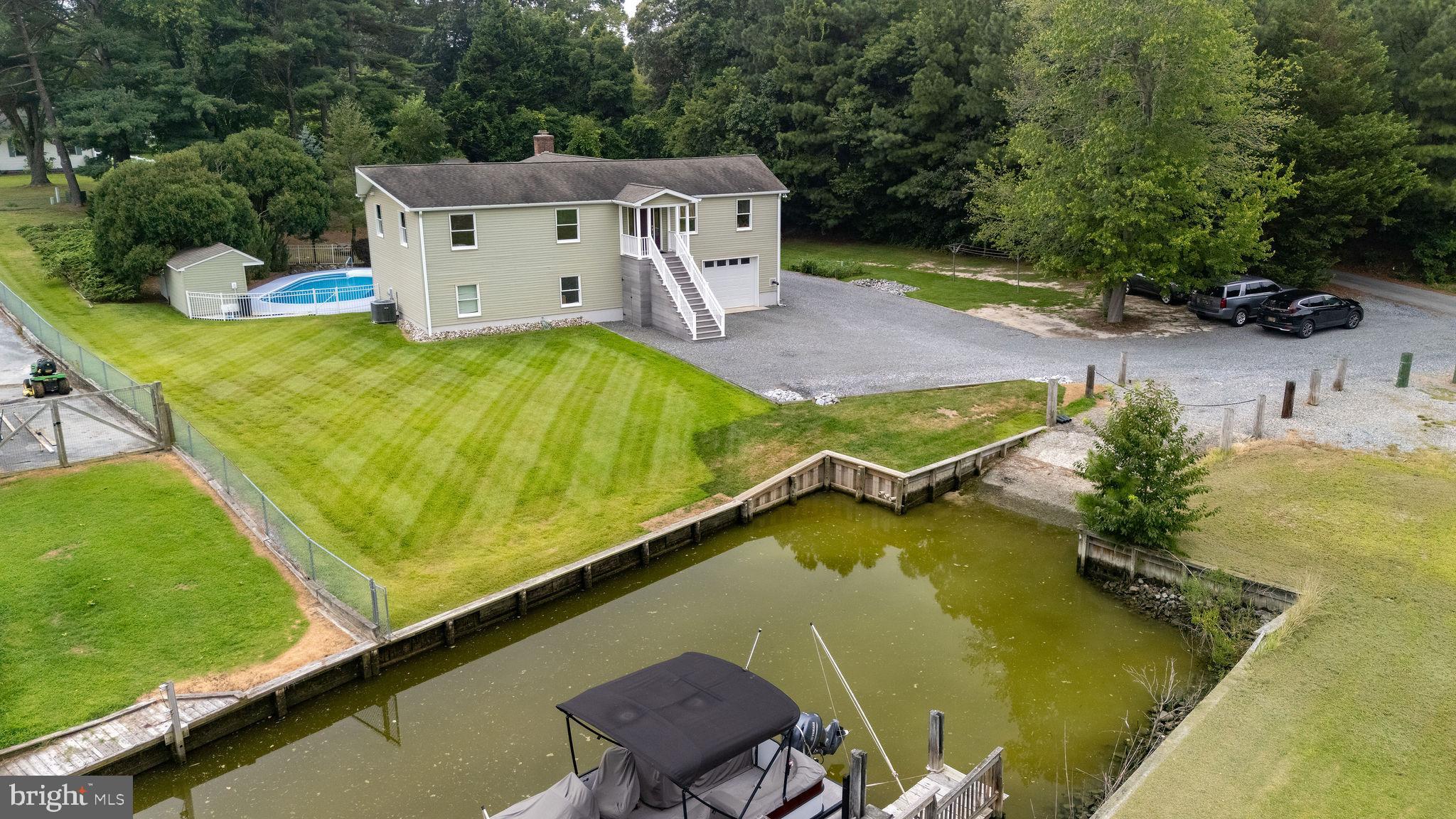 Waterfront Living with Endless Potential – Private Raised Ranch with Pool and Dock Access
Welcome to your serene escape on Burton’s Prong, offering direct access to Herring Creek and the Rehoboth Bay. This spacious 3-bedroom, 3-bathroom raised ranch offers a rare combination of waterfront access, privacy, and versatility — perfect for year-round living, a vacation getaway, or a multi-generational retreat.
Upstairs Comforts (Approx. 2,100 sq ft):
Step into a bright and open living space featuring an expansive den with a cozy wood-burning fireplace and direct access to the deck, patio, and in-ground pool — ideal for entertaining or simply relaxing by the water. The open-concept kitchen and dining area offer great flow and functionality, complemented by a full utility room and space ready for dumbwaiter installation if desired.
Three generously sized bedrooms feature HEPA filters, extra-wide 3-ft doorways, and handicap-friendly door handles. Two full bathrooms add to the convenience, while electric baseboard heating and central A/C provide comfort year-round. Landline-ready rooms throughout the home ensure connectivity where you need it.
Lower Level Potential (Approx. 2,100 sq ft):
The finished lower level includes a full bathroom, epoxy-coated cement flooring, painted drywall, a large open space with a pellet stove, and additional appliances — including a refrigerator and freezer. This level also houses the garage area, offering flexibility for storage, workshop, or recreation.
Outdoor Features:
•