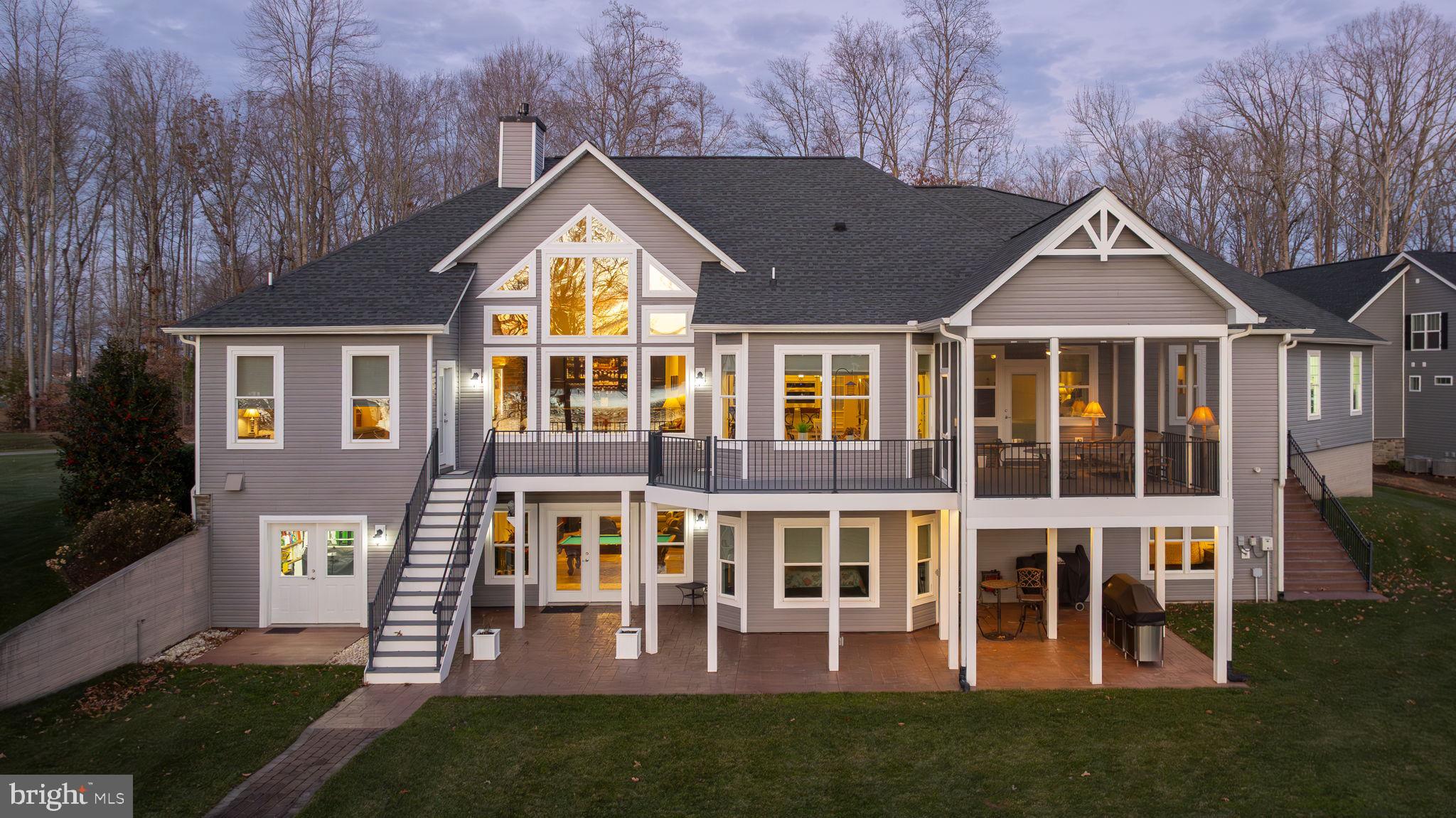 Presenting 95 Olive Branch Court—an extraordinary tribute to waterfront luxury in Noah’s Landing on the private side of Lake Anna. Framed by sweeping, unobstructed water views and unforgettable sunsets, this custom-built craftsman masterpiece was constructed in 2017 by Spartan Homes and is perfectly positioned on a .75-acre lot with approximately 150 feet of pristine rip-rap-protected shoreline, a private boathouse, and deep, calm waters ideal for year-round lake enjoyment. Offering over 5,000 square feet of impeccably designed living space, this home delivers a seamless blend of refined sophistication and relaxed lakeside living. With 5 expansive bedrooms, including a main-level bedroom suite, and 4.5 beautifully appointed bathrooms, the home provides luxurious accommodations for both everyday living and hosting guests. The primary suite showcases a tray ceilings, a large walk-in tiled shower, double vanity, and his-and-her walk-in closets with custom shelving. Throughout the home, refined architectural details abound—vaulted and 9’+ ceilings, rich hardwood flooring, and walls of glass that flood the interior with natural light while framing breathtaking lake views. The stunning gourmet kitchen features granite countertops, stainless steel appliances, breakfast bar seating, a breakfast room with bay window, and an exquisite custom bar—perfect for entertaining. Additional highlights include an integrated Sonos sound system, water softener system, stone gas fireplace with built-in cabinetry, and thoughtfully designed living spaces that flow effortlessly indoors and out. The massive finished basement expands the living space even further, offering a mini kitchen, family room, recreation area, two additional bedrooms, two full baths, and ample storage—ideal for extended stays or entertaining. Outdoor living is equally impressive, featuring a composite deck overlooking the lake, a large screened-in porch, custom exterior lighting, and a walkway leading directly to your shoreline and boathouse. Completing the property is an impressive (1,228 square foot) 4-car attached garage with a 7,000-lb lift and separate workshop room, paved driveway, lake-fed irrigation system with 12 zones, and high-speed fiber internet through Firefly. This exceptional waterfront estate offers an unmatched lifestyle in a prime Lake Anna location—where luxury, comfort, and unforgettable lake memories come together.