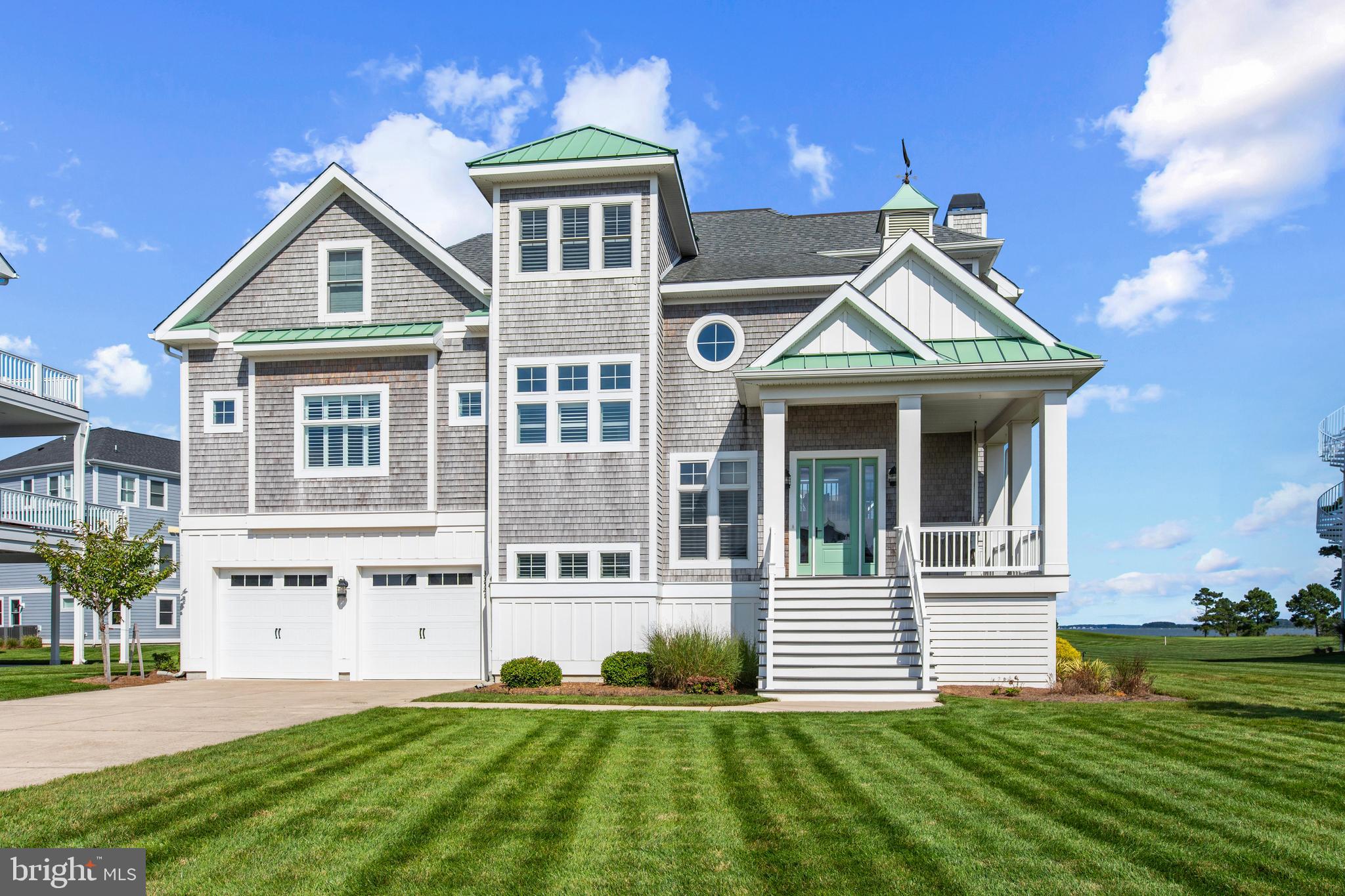 Blending timeless coastal style, superior craftsmanship, and refined finishes, this custom Echelon Grand Cayman model stands among the most impressive residences in The Peninsula. With six bedrooms and five-and-a-half baths, the home commands sweeping Indian River Bay vistas from nearly every room, perfectly framed by the 7th hole of the Jack Nicklaus Signature Golf Course—a rare combination of breathtaking water and golf course views.

Authentic cedar-shake siding and a welcoming covered front porch establish irresistible curb appeal, hinting at the attention to detail found throughout. Step inside to a dramatic two-story foyer and discover three spacious levels united by 10-foot ceilings, wide-plank hardwood flooring, plantation shutters, and a freshly painted neutral palette. Walls of Anderson windows and tall glass doors flood the open concept interior with natural light and showcase the panoramic scenery that defines this extraordinary home.

At its heart, an elegant great room features a coffered ceiling and gas fireplace, flowing effortlessly into the dining area and an entertainer’s dream kitchen. The chef will appreciate the striking 13 × 10 L-shaped island wrapped in granite, 42-inch soft-close cabinetry with glass displays, pendant and under-cabinet lighting, high-end GE Café appliances including a five-burner gas cooktop and double dishwashers, a convection-option microwave, timeless herringbone subway-tile backsplash, and an oversized walk-in pantry. Sliding doors invite you to dine alfresco on the open-air deck or unwind in the screened porch while soaking in dazzling sunsets.

The main-level primary suite provides a private retreat with tray ceiling detail, dual walk-in closets, and direct porch access. Its spa-inspired bath offers a wrap-around dual-sink vanity, frameless glass shower with bench seating, and a separate water closet. Travel upstairs by staircase or elevator to find four generous bedrooms—two with ensuite baths—all enjoying shimmering Bay views. The lower level is ideal for casual gatherings with a sprawling recreation room,  a sixth bedroom, and full bath—perfect for overnight guests.

Thoughtful touches abound, including 8-foot solid-core interior doors, integrated surround-sound, a trash compactor, wall-mounted flat-screen TVs, and a dedicated irrigation system. The .28-acre homesite offers ample space for a future pool and features a large driveway that easily accommodates up to six vehicles, providing both convenience and functionality.

Best of all, you’re a short stroll from The Peninsula’s award-winning clubhouse and Lakeside Village, home to indoor, outdoor, and wave pools, a state-of-the-art fitness center, tennis and pickleball courts, walking trails, on-site dining, and a lively calendar of year-round events. 33521 Tiderunner Avenue is more than a house—it’s a statement in coastal luxury and effortless resort living.  Schedule your private showing today!