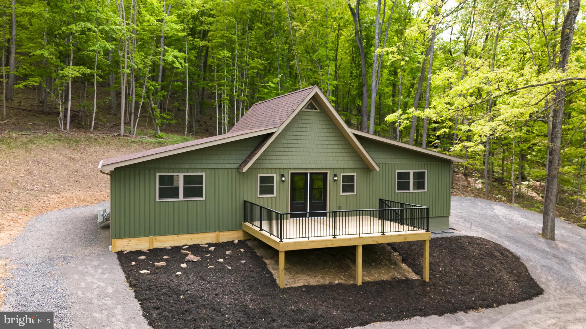 Stunning modern chalet in a private mountain lake community! This once rustic cabin has been completely transformed into a one-of-a-kind mountain/lake retreat, thoughtfully renovated with quality craftsmanship and materials—everything updated except the original framing. Tucked away in a hidden lake community in the WV hills, the home sits on a generous 5.62-acre parcel surrounded by towering hardwoods, offering exceptional privacy and natural beauty. Inside, you’ll find a show-stopping custom kitchen featuring quartz countertops, a large island, and brand-new stainless steel appliances. The open interior is highlighted by soaring vaulted ceilings with tongue-and-groove pine, creating a warm yet modern aesthetic. The enormous primary suite includes a walk-in closet and a beautifully finished bath with a custom tiled shower. The main bath also features a custom tiled shower along with a convenient utility area with washer and dryer. A versatile loft area provides additional space for a bedroom, office, or cozy sitting area. Step outside to a massive deck overlooking a fire-pit area—perfect for entertaining or relaxing under the stars. Perched on a hillside among towering oaks, the home is just a short distance from the community lake and beach, offering easy access to swimming, kayaking, and lakeside enjoyment. A rare opportunity to own a fully re-imagined mountain retreat that blends modern design with peaceful lake community living.