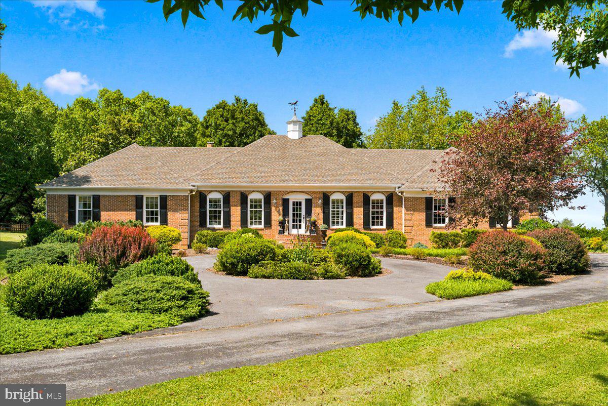 Escape to your own private botanical oasis in the heart of the Shenandoah Valley! Situated on just over two pristine acres backing to scenic open fields, this meticulously maintained, all-brick rancher offers main-level living at its absolute finest. Designed for both peaceful seclusion and effortless entertaining, the home features a spacious main floor layout complete with a formal living room, a separate elegant dining room, and a cozy family room boasting rich cherry wood floors and an electric fireplace that can easily be made into a regular wood fireplace. At the heart of the home is a gourmet kitchen, perfectly equipped for preparing meals for your loved ones.
The true highlight of the main level just might be the conditioned four-season sunroom. It offers a comfortable, front-row seat to a spectacular, masterfully landscaped backyard that feels like a professional botanical garden, with paths winding through a diverse array of seasonal flowers and mature trees curated to bloom year-round. For outdoor relaxation, you can stroll the grounds or unwind in the screened-in gazebo while overlooking the vast, peaceful fields that border the property.  The living space extends to a beautifully finished basement, featuring a massive recreation room and a private, optional guest suite with a full bathroom that provides the perfect retreat for visitors. Practical amenities abound with an attached two-car garage sitting adjacent to a dedicated storage and potting room tailored for gardening needs, complemented by two additional storage sheds hidden discretely by foliage. Located within walking distance to the Shenandoah Valley Golf Club, this home is a rare find that perfectly blends meticulous upkeep, unparalleled natural beauty, and a prime location for outdoor enthusiasts. Also, for you horticultural enthusiast there are a variety of trees on the property, including an assortment of eight Japanese maples.
