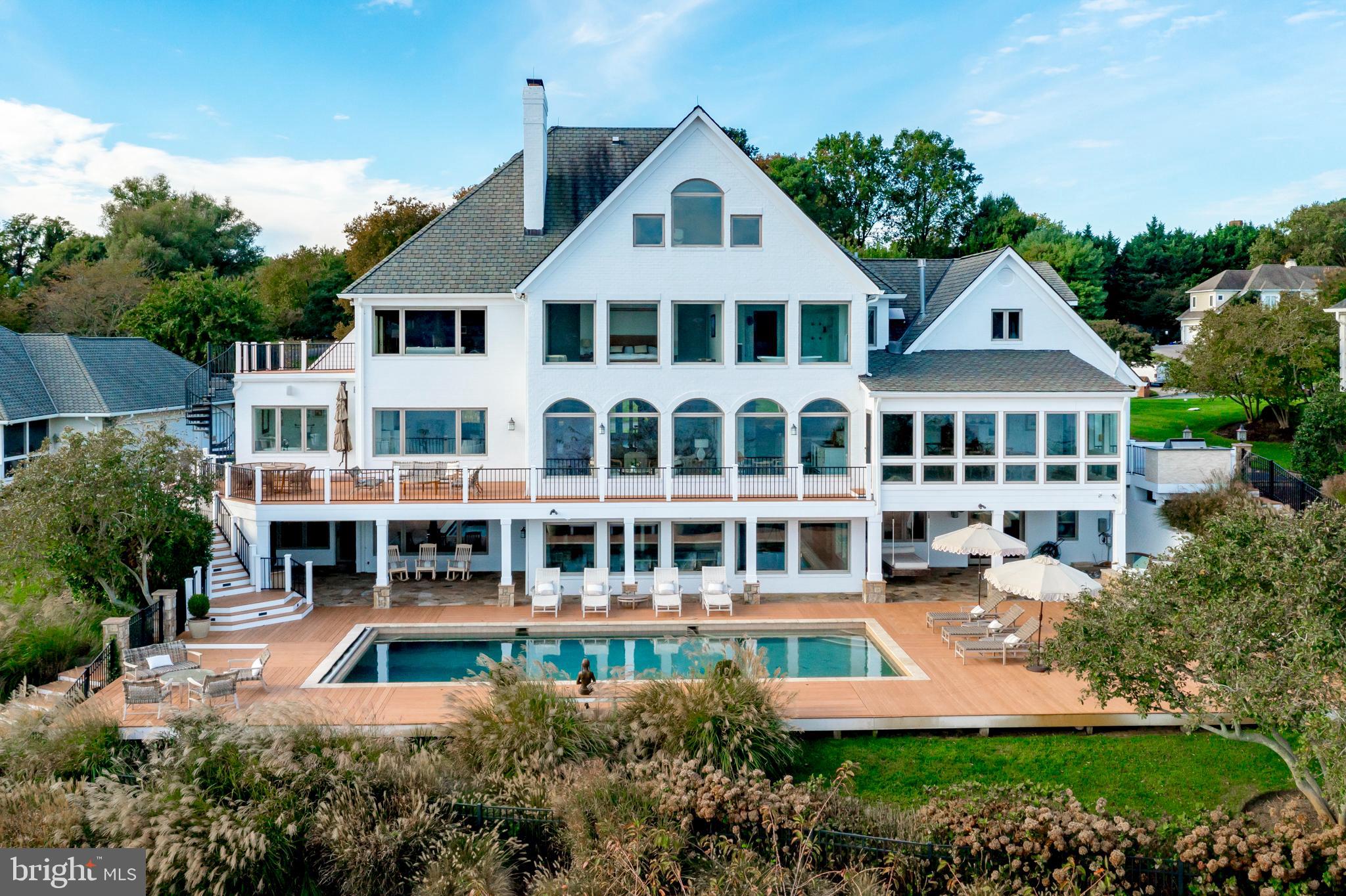 This Severn River Waterfront Estate is a rare and breathtaking Annapolis retreat. Experience the ultimate in waterfront living  in this exquisite  residence,  a true masterpiece offering unparalleled panoramic water views. Nestled on a pristine one-acre site in the prestigious Point of The Downs, this home has been updated  creating the ideal setting for unforgettable family gatherings, holidays, and retreats. Spanning four levels of living space, this residence boasts designer finishes. The  chef’s kitchen is a showstopper, featuring elegant white cabinetry, a Sub-Zero refrigerator, a custom bar area, and multiple dining spaces. The luxurious primary suite is a private sanctuary, offering breathtaking water views. Two home offices provide the perfect work-from-home setup, while an elevator ensures seamless access to all levels. Indulge in exceptional amenities designed for both relaxation and entertainment. Six gas fireplaces create warmth and ambiance, while the in-home theater offers the ultimate cinematic experience. A private gym, sauna, and steam room provide a space for wellness and rejuvenation. Outside, the PebbleTec waterside pool, hot tub and outdoor fireplace create a resort-style atmosphere perfect for entertaining or unwinding. For boating enthusiasts, the private deep-water pier features an eight-foot mean low water depth, three slips, and two  lifts with 12,000- and 20,000-pound capacities. A three-car garage with 2 electric charging stations and circular driveway provide ample parking for residents and guests alike.