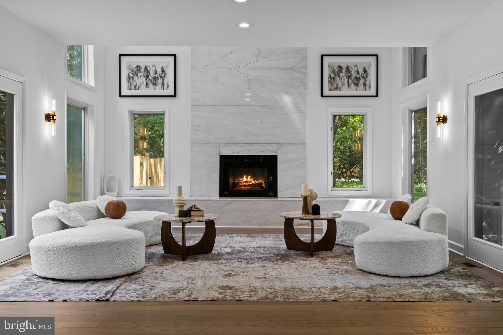 Tucked away on a serene and private two-acre wooded setting, this exquisitely renovated contemporary residence offers a rare fusion of modern elegance and effortless living. Thoughtfully reimagined, the five-bedroom, three-and-a-half-bath home is defined by sunlit interiors, soaring spaces, and timeless sophistication. The main level welcomes with 10-foot ceilings, white oak flooring, and streams of natural light from expansive windows and skylights. The airy living room, anchored by a dramatic double-height white marble fireplace, opens to terraces on either side—perfect for morning coffee or evening gatherings. The adjoining dining room blends classic style with indoor-outdoor flow, offering direct access to the rear patio and pool. At the heart of the home, the gourmet kitchen features top-tier appliances, a generous quartz island, custom cabinetry, and a casual breakfast alcove. The adjoining family room, with its striking stone double-height fireplace, built-in cabinetry, and wet bar, creates an inviting setting for relaxed entertaining. Beyond, a breathtaking sunroom showcases cathedral ceilings, exposed beams, and a curved wall of glass, seamlessly connecting to the patio and pool—an inspiring all-season retreat. Upstairs, the primary suite is a luxe escape, offering a private sitting room, walk-in closet, and spa-like bath with soaking tub, dual vanities, and oversized rain shower. A second en suite bedroom features a lofted hideaway, while three additional bedrooms share a beautifully appointed hall bath. A second-floor laundry adds everyday convenience. The lower level provides flexible finished space and a cedar-lined walk-in closet, with ample unfinished storage as well. Outdoors, the property unfolds as a private resort—sparkling pool, soothing spa, expansive patio, and lush landscaping create an atmosphere of tranquility and leisure. A circular front drive and separate private drive to the side-entry two-car garage offer ease and convenience, complemented by new fencing for privacy and peace of mind. The home is further enhanced by a three-zone HVAC system for optimal comfort and efficiency.Modern yet inviting, secluded yet connected—this exceptional property is a rare opportunity to own a contemporary retreat that embodies style, comfort, and sophistication.