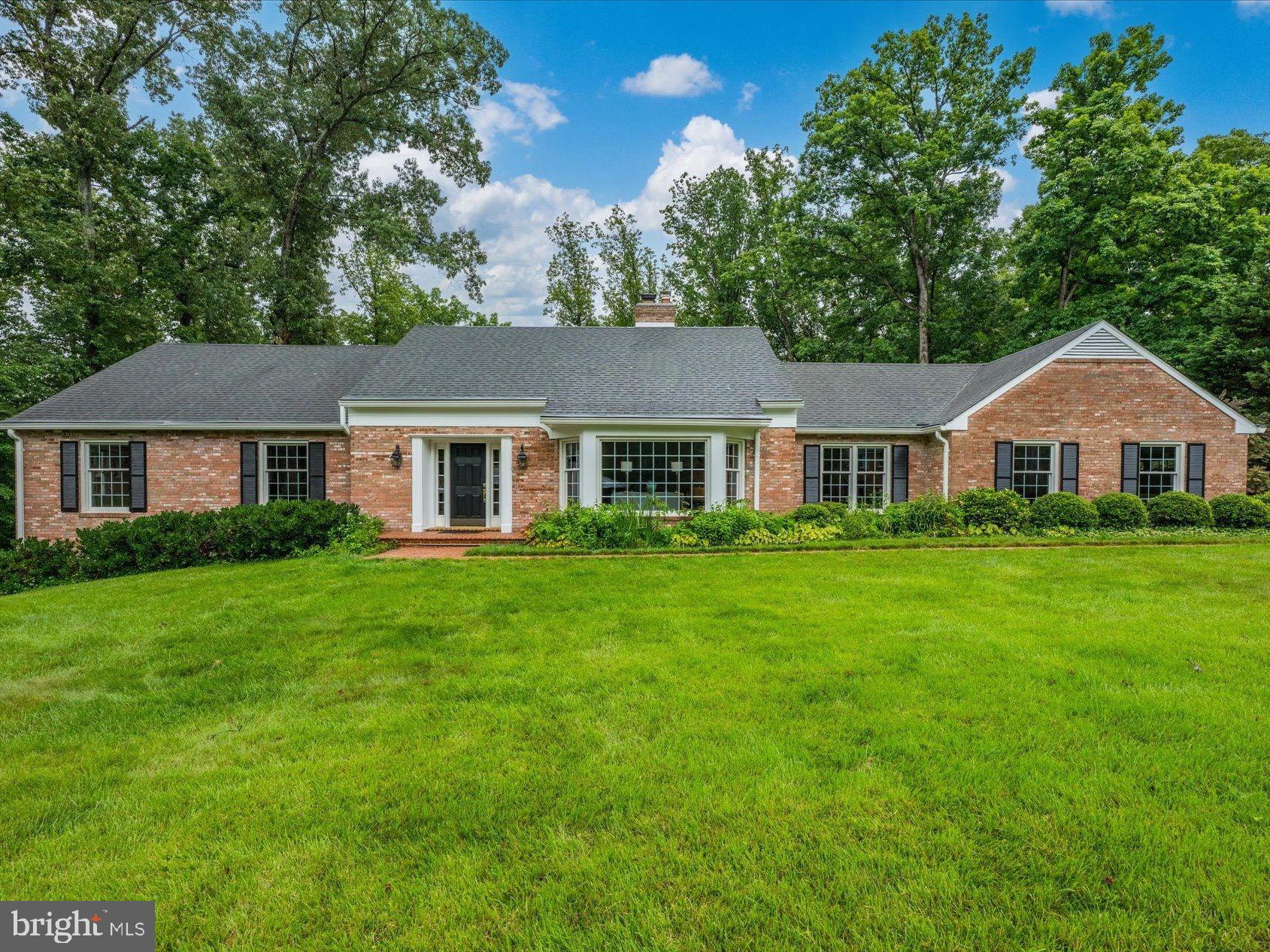 Tucked on a quiet cul-de-sac in the coveted Olde Swinks Mill Estates neighborhood of McLean, this beautifully updated all-brick home delivers the rare combination of main-level primary suite living, resort-style outdoor amenities on a beautiful acre lot  backing to Scott's Run parkland.

Set on a private, wooded lot enveloped by mature trees, the home's classic brick exterior and lush landscaping make an immediate impression. Inside, a gracious two-story foyer welcomes you into this attractively updated home with a flowing floor plan spanning approximately 4,500 square feet across three levels. Wainscoting, crown molding, and built-in bookshelves speak to the home's timeless character throughout.

The heart of the main level is a fully renovated chef's kitchen featuring custom white cabinetry, Calacatta marble countertops and island, a professional Sub-Zero refrigerator, high-end range with stainless hood, and a butler's pantry with glass-front cabinetry and additional marble counter space. The kitchen opens seamlessly to a sun-filled breakfast area and an inviting family room with a wood-burning fireplace, built-ins, and French doors to the deck — an effortless flow ideal for everyday living and entertaining alike. A formal living room and separate dining room round out the primary gathering spaces. The library offers large windows and a wall of built-ins. The main level is complete with the powder room laundry room and two car side load garage. 

The main-level primary suite is a true retreat, offering generous proportions, a custom walk-in closet system, and a spa-inspired en suite bath completely renovated in 2021. The primary bath showcases marble tile floors, a freestanding soaking tub with polished brass fixtures, an oversized frameless glass shower with Calacatta marble surround, dual-sink vanity with quartz countertop, crystal chandeliers, and designer brass hardware throughout — a sanctuary of refined elegance. A powder room, also updated in 2021, and main-level laundry complete this level.  A library with a wall of built-ins, a powder room, laundry room and side-load garage complete the main level. 

The second level features spacious second and third bedrooms with a completely renovated Jack-and-Jill bath and a fourth en suite bedroom suite with vaulted ceiling and renovated bath.  The second level also has a large unfinished attic for storage or can be used to add a third bath.  The finished lower level adds even more living space with a large recreation room, a fifth bedroom with a full bath, fireplace and French doors opening directly to the pool — making it a natural extension for guests or multigenerational living. The huge storage room offers plenty of space to add an exercise room and / or media room. 

The private rear grounds are simply spectacular: a swimming pool is set amid lush perennial gardens, flowering borders, and a wooded backdrop that delivers extraordinary privacy. Multiple deck levels offer ideal spaces for outdoor dining and relaxation. 

New driveway (2023), whole-house generator (2020), new roof (2011), rebuilt chimneys (2024), Gutter Helmet system, irrigation, and new garage door (2025) ensure worry-free ownership for years to come. Minutes to Tysons Corner, the Silver Line Metro, I-495, Georgetown Pike, Reagan National and Dulles International airports, Scotts Run and Great Falls National Park.