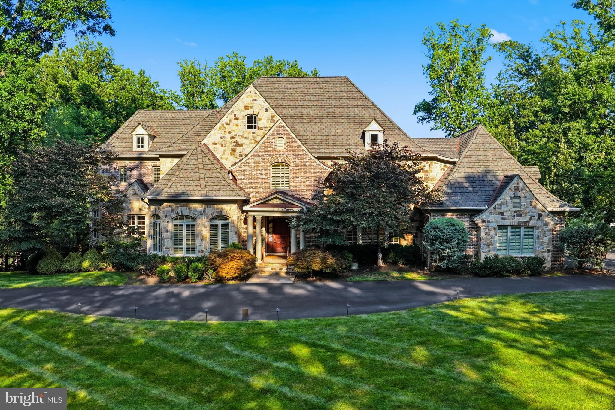 Set on 1.53 beautifully landscaped and exceptionally private acres in McLean’s coveted Woodside Estates, 1239 Daleview Drive is an extraordinary stone manor where timeless architecture, meticulous craftsmanship, and resort-caliber amenities come together on a remarkable scale. Custom-built by Solitaire Homes, the residence offers nearly 11,800 square feet of sophisticated living and entertaining space, with an elevator serving every level, a four-car garage, extensive custom millwork, rich hardwood flooring, multiple fireplaces, and thoughtfully designed rooms that balance elegance with everyday comfort.

A dramatic foyer introduces the home’s beautifully proportioned interiors and establishes an immediate sense of quality. Formal living and dining rooms provide a refined backdrop for entertaining, while the expansive family room creates a warm and inviting gathering space. At the heart of the home, the gourmet kitchen is designed for both serious cooking and effortless hosting, offering generous preparation space, abundant cabinetry, and an adjoining breakfast area filled with natural light. A private study, custom built-ins, detailed crown molding, and carefully selected finishes further elevate the main level.

Upstairs, four spacious bedroom suites provide exceptional privacy and comfort. The primary suite is a true retreat, distinguished by a dramatic coffered ceiling, ambient lighting, a private sitting area, a luxurious spa-inspired bath, and two fully outfitted walk-in closets. Each additional bedroom offers its own en suite bath, creating an ideal layout for family members and overnight guests alike.

The fully finished lower level extends the home’s entertainment possibilities with a game room, fitness space, wet bar, additional bedroom accommodations, and direct access to the rear grounds. Outdoors, extensive stone hardscaping surrounds a spectacular saltwater pool and creates multiple areas for dining, lounging, and entertaining. A pergola adds an intimate setting for relaxed evenings, while the separate two-level pool house spans more than 1,100 square feet and delivers an exceptional destination for hosting guests or enjoying the property’s resort-like atmosphere.

With five bedrooms, six full and four half baths, grand yet comfortable interiors, and an extraordinary collection of indoor and outdoor amenities, 1239 Daleview Drive offers rare privacy, enduring quality, and an elevated lifestyle just minutes from Tysons, downtown McLean, and the region’s major commuter routes.