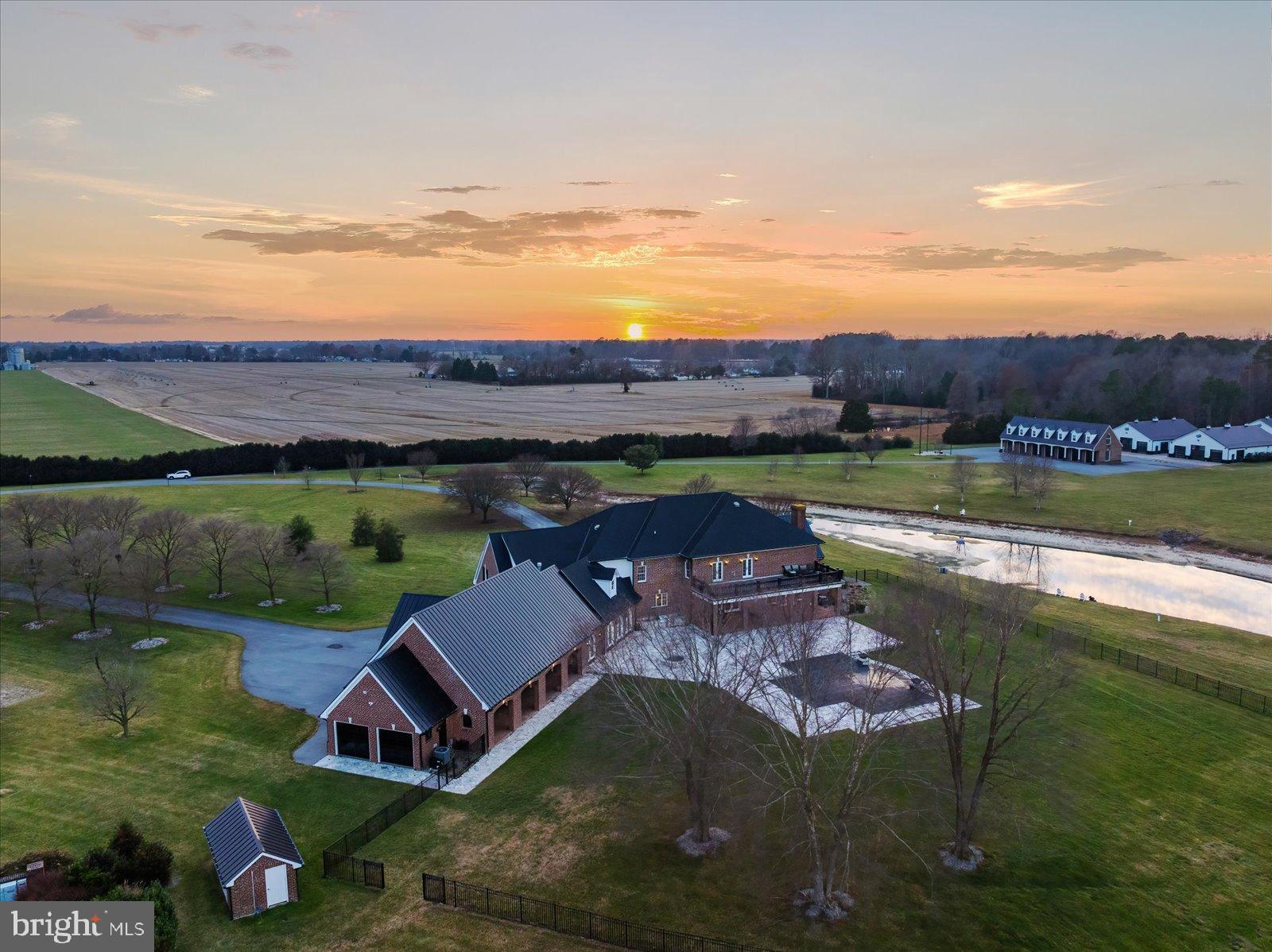 A truly rare offering for the discerning auto enthusiast, this exceptional 58.48-acre Eastern Shore estate is a masterfully designed luxury compound where architectural elegance meets world-class automotive accommodations. Introduced by a private gated entrance and tree-lined circular drive, the stately brick home immediately conveys the scale, privacy, and prestige of this one-of-a-kind property.
The main residence spans over 9,364 square feet and is thoughtfully designed for refined living and grand-scale entertaining. A dramatic two-story foyer with sweeping double staircases opens to richly appointed formal and informal living spaces accented by custom millwork, crown moldings, hardwood flooring, and four fireplaces. At the heart of the home, the chef’s kitchen impresses with coffered ceilings, expansive island, commercial-grade range, double wall ovens, and premier Viking, Sub-Zero, and Wolf appliances, along with an induction cooktop and icemaker. A well-appointed butler’s pantry ensures seamless entertaining, while the adjoining Grill Room—featuring an infrared grill, Viking beverage cooler, and Sub-Zero icemaker—offers a relaxed gathering space.
The primary suite is a private retreat with fireplace, mood lighting, generous walk-in closets, and dual doors leading to a private balcony overlooking the grounds. The spa-inspired bath includes double vanities, a tiled shower, and soaking tub. All additional bedrooms in the main residence are ensuite, offering comfort and privacy for family and guests.
Outdoor living rivals a private resort, highlighted by a 40’ x 20’ heated saltwater infinity pool with swim ledge, hot tub, outdoor kitchen, covered porch, expansive patios, and firepit—perfect for year-round enjoyment amid mature landscaping, a tranquil pond, and sweeping rural views.
Automobile collectors will appreciate the estate’s unparalleled garage facilities. A detached brick automotive gallery features a nine-bay, climate-controlled showcase garage with CHI aluminum tinted glass doors, polished concrete floors, and premium climate control—ideal for preserving and displaying a museum-quality collection. Above, a fully appointed three-bedroom, two-bath guest residence offers a kitchen and multiple living spaces. Two additional fully insulated, climate-controlled 50’ x 75’ garages with 12-foot overhead doors and professional-grade lifts provide exceptional flexibility. An oversized storage building and run-in to the rear further enhances the property’s versatility.  Hobbyists, from automobile collectors to equestrian enthusiasts, will be delighted to make use of the many large accessory structures on the property.  
Additional features include a comprehensive security and surveillance system, private gated entrance, 60-zone irrigation system, whole-property surround sound, & Comcast fiber internet.
This is more than a home—it is a destination estate offering an elevated lifestyle for those who value privacy, craftsmanship, and automotive excellence in a refined Eastern Shore setting.

IMPORTANT NOTES: Property consists of three parcels with separate addresses/taxes, portions of which are leased for agricultural use through December 2025.  The irrigation system has a mainline break beneath a garage and will not be repaired by the seller. Quotes for repair or replacement are available for review.in documents. Front garage has suffered water damage and in the process of being remediated but seller will not be making repairs to the garage or apartment.  Estimates for the remediation (which seller is doing) and the repair of damaged area is uploaded in MLS disclosure docs.  All agents/buyers touring MUST sign a Hold Harmless Document prior to entering the garage/apartment.  Property is being sold AS-IS/WHERE-IS with all faults. Contact listing agent(s) with any questions.  ***Please do not enter lane to property without a confirmed appointment.