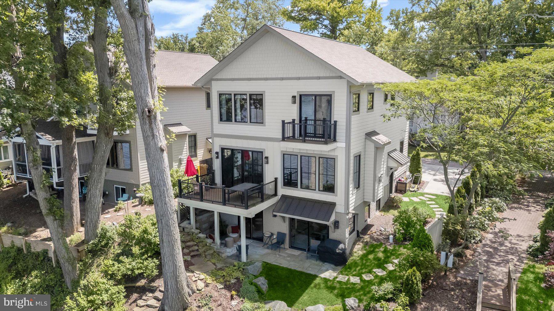 Rare opportunity to own a custom-designed waterfront home on the South River. Built in 2022, this exceptional residence offers more than 3,000 square feet of finished living space, panoramic water views, modern construction, and energy-efficient features. Situated on a quiet private brick-paved lane with only three homes, the property enjoys approximately 0.60 miles of open-water views across the South River toward the Riva Bridge. The open-concept main level was designed to maximize natural light and showcase the waterfront setting, featuring hardwood floors, a gourmet kitchen with GE Profile appliances, a six-burner dual-fuel gas range, granite countertops, custom cabinetry, an imported Portuguese tile backsplash, walk-in pantry, and a spacious living area with a gas fireplace and oversized sliding glass doors leading to a waterside deck. A dedicated main-level office provides the perfect work-from-home space. The upper level includes a luxurious waterfront primary suite with vaulted ceilings, a private balcony, sitting area, service bar with beverage refrigerator, remote-controlled blackout blinds, walk-in closet, and a spa-inspired bath featuring a steam shower. Two additional bedrooms and baths provide comfortable accommodations for family and guests. The finished walkout lower level offers radiant-heated tile floors, a full wet bar, flexible recreation space, abundant storage, and direct access to a stone waterfront patio surrounded by professionally designed rain gardens. Exterior features include HardiePlank siding, stone accents, Trex decking, a covered front porch, and off-street parking. Residents of Sylvan Shores enjoy access to private community amenities, including waterfront parks, a boat ramp, kayak and canoe storage, fishing pier, boat slips, swimming areas, and a 40-acre community park with recreational facilities. Conveniently located just minutes from Annapolis Town Center, downtown Annapolis, Route 50, and I-97, this is a rare offering that combines modern waterfront living, exceptional views, and one of the South River's most desirable locations.