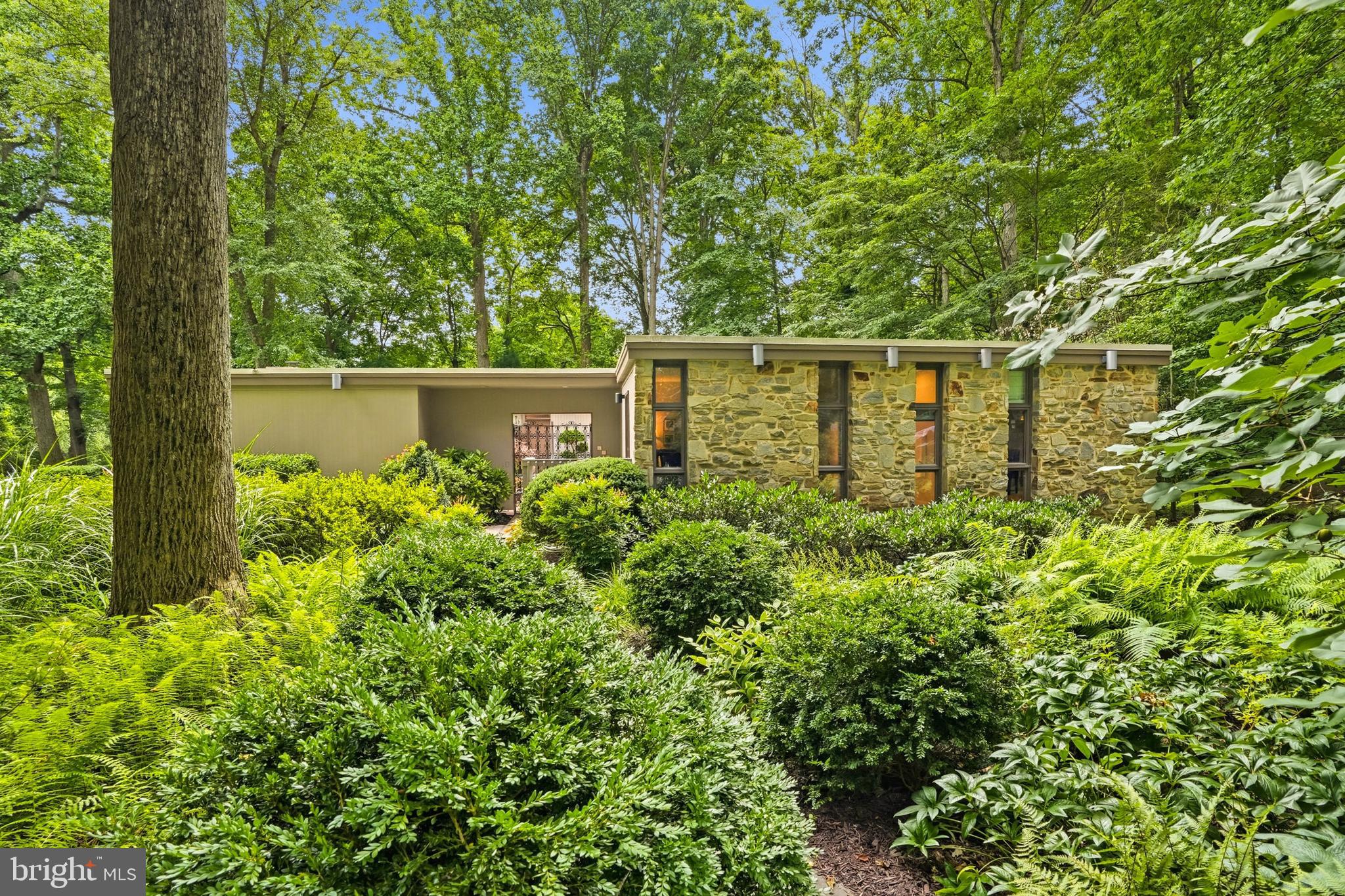 Tucked into a premium 0.62-acre corner lot in the prestigious Longfellow neighborhood of West Columbia, this exquisitely maintained and thoughtfully updated mid-century contemporary offers over 3,400 square feet of beautifully finished living space, where timeless architecture meets a private oasis of lush, professionally landscaped grounds * An ornate iron gate welcomes you into a stunning courtyard surrounded by curated landscaping, creating a memorable entrance to both the home and attached two-car garage with EV charger. Inside, rich natural hardwood floors flow throughout the main level, beginning in the inviting foyer and continuing into light-filled living spaces designed for both everyday comfort and effortless entertaining * The gourmet eat-in kitchen is the heart of the home, featuring quartz countertops, custom cabinetry, and premium appliances, including an induction cooktop, separate downdraft grill, built-in microwave, and oven. A sunny breakfast nook opens seamlessly to the cozy family room, where custom built-ins and a dramatic wall of windows frame picturesque views of the surrounding landscape. The adjacent dining room opens through expansive French doors out to a recently added screened porch and oversized deck, creating the perfect setting for indoor-outdoor living * The main level also offers the convenience of a laundry room, making one-level living a breeze. The elegant living room is anchored by a wood-burning fireplace, complemented by recessed lighting and abundant natural light * Designed with flexibility in mind, the home features six above-grade bedrooms and three beautifully renovated full bathrooms. A thoughtfully designed addition serves as an ideal in-law suite, guest quarters, private home office, or multigenerational living space, complete with its own separate entrance, two bedrooms, and a full bath * The spacious primary suite provides a peaceful retreat with three closets and a beautifully renovated en-suite bath. An updated hall bathroom serves the additional bedrooms with timeless style * The finished walk-out lower level expands the home’s versatility with a large recreation room featuring custom built-ins, an office or exercise room, an additional storage room, each with windows that welcome natural light, and a generous utility room with direct access to the backyard * Throughout the home, upgraded windows and sliding doors, custom window treatments, and recessed lighting enhance both comfort and efficiency * Outside, the professionally designed landscape includes an irrigation system, architectural exterior lighting, mature plantings, and an expansive grassy side yard perfect for recreation, gardening, or simply enjoying the peaceful setting * Ideally located just minutes from Centennial Park, Wilde Lake, Hobbits Glen and Fairway Hills golf courses, and the vibrant Columbia Town Center and Merriweather District, residents enjoy exceptionThroughout the home, upgraded windows and sliding doors, custom window treatments, and recessed lighting enhance both comfort and efficiency * Outside, the professionally designed landscape includes an irrigation system, architectural exterior lighting, mature plantings, and an expansive grassy side yard perfect for recreation, gardening, or simply enjoying the peaceful setting * Ideally located just minutes from Centennial Park, Wilde Lake, Hobbits Glen and Fairway Hills golf courses, and the vibrant Columbia Town Center and Merriweather District, residents enjoy exceptional shopping, dining, entertainment, and year-round cultural events. Convenient access to Route 108 and every major commuter route between Baltimore and Washington, D.C., makes this remarkable property as practical as it is beautiful * A rare opportunity to own an architecturally distinctive home that seamlessly blends timeless mid-century design, modern updates, flexible living spaces, and an unparalleled natural setting in one of Columbia’s most sought-after neighborhoods *