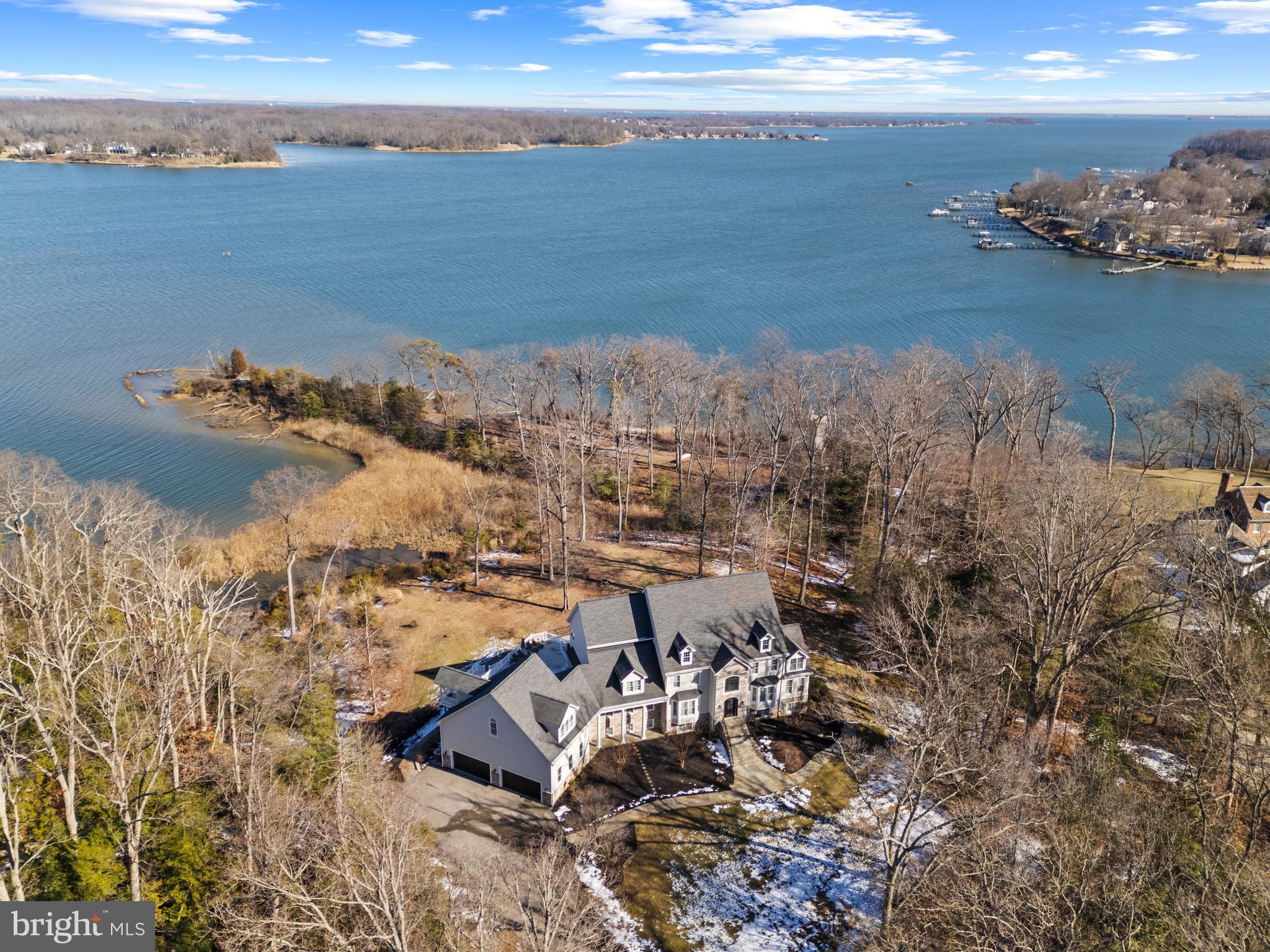 A rare gem, this extraordinary estate with pool is nestled on 8.89 acres of pristine waterfront and offers breathtaking views of the South River and unparalleled privacy. A gated entrance leads to a secluded sanctuary, where mature trees frame the property, creating one of the most exclusive settings in the Annapolis area. With approximately 1,600 feet of water frontage, a private sandy beach, and a deep-water pier featuring multiple slips, a lift, and an impressive 10' MLW, this is a true waterfront paradise. Designed for grand entertaining and serene relaxation, the outdoor spaces are a masterpiece. A waterside pool with waterfall feature, expansive flagstone patios, and spacious deck provide endless opportunities to soak in the stunning surroundings. Inside, refined luxury meets thoughtful design. An elevator services every floor making all the features easily accessible.  The lower level is for entertaining with a private theater, custom wet bar, wine cellar for over 1,000 bottles, game room and a gym; offering a diverse range of activities to delight guests and family members of all ages and interests.  The main level boasts two generous living areas, a stunning open-concept gourmet kitchen with Wolf and Sub-Zero appliances, coffee bar, island seating, and access to the enormous deck overlooking the pool and waterfront.  The highlight of the main level is a fully equipped bar with brass rail, mirrored shelves and balcony.  Feel like you are in an English pub everyday!  A formal dining area, study nook, large laundry room, full bath, powder room, and a two-story, four-car garage complete the space. The upper level features three spacious guest suites, each with a private bath, and an opulent primary suite beyond compare. With dual spa-like bathrooms, an extravagant walk-in closet, a dry bar, and a private office/bedroom with its own ensuite and separate entrance, this retreat is the pinnacle of luxury. Stroll the sprawling property and venture out to the point of land that features a sitting area, swing, sandy beach and private pier on the South River. Welcome Home!