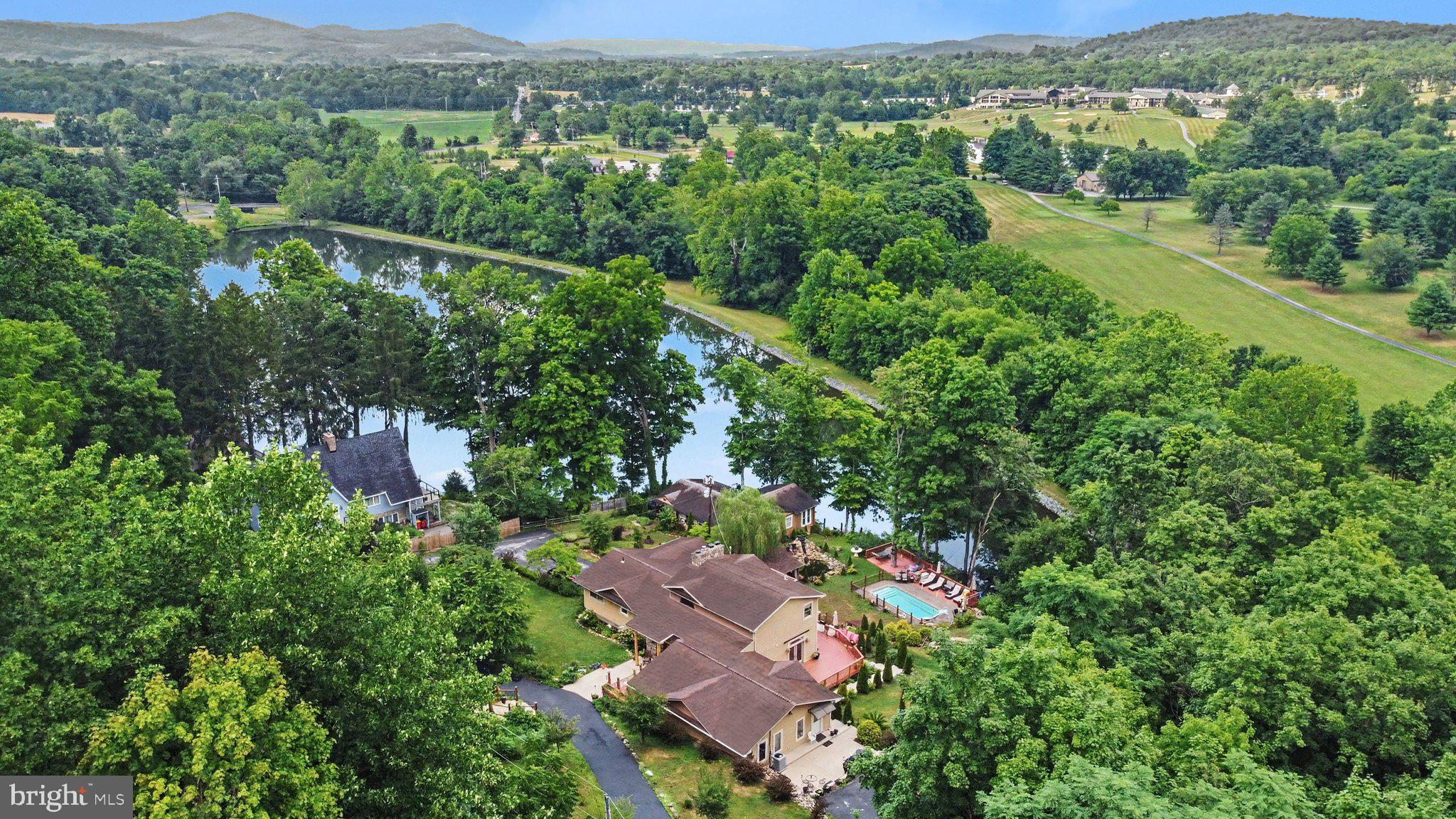 Set on 1.34 private, wooded acres directly on the shores of Charnita Lake, this 6-bedroom, 5-bath waterfront estate blends rustic mountain charm with the space and flexibility today's buyers are looking for. Whether you're looking for a spacious retreat, housing multiple generations under one roof, or building a turnkey short-term rental in the heart of the Ski Liberty corridor, this property is rich with options. Step inside through the stone-and-timber entry and you're greeted by a great room anchored by a floor-to-ceiling stone fireplace, rich hardwood floors, and walls of windows framing the lake and wooded hillside beyond. The open living and dining areas flow onto multiple rear decks, perfect for morning coffee over the water or evening entertaining under the trees. With three full kitchens — including a gourmet kitchen and two additional kitchens featuring their own islands — plus bedroom-level laundry, the layout is purpose-built for multiple households, or multiple sets of guests, to live independently and comfortably. Wake up, walk out your door, and be on the water: the property offers direct lake access for kayaking and swimming, with a private dock overlooking one of the most scenic stretches of the lake. Cool off instead in the saltwater pool, or gather around the outdoor spaces built for entertaining. This is four-season living at its best. Ski Liberty is just minutes away for skiing, golf, and clubhouse amenities, and you're a short drive from the charm of Fairfield and the history of Gettysburg. The Maryland line is just minutes south, putting Baltimore and DC within easy reach. Whether you're envisioning a multigenerational compound, a high-performing lake house rental, or your own private waterfront escape, 26 Lakeside Trail offers a rare combination of privacy, space, and location.