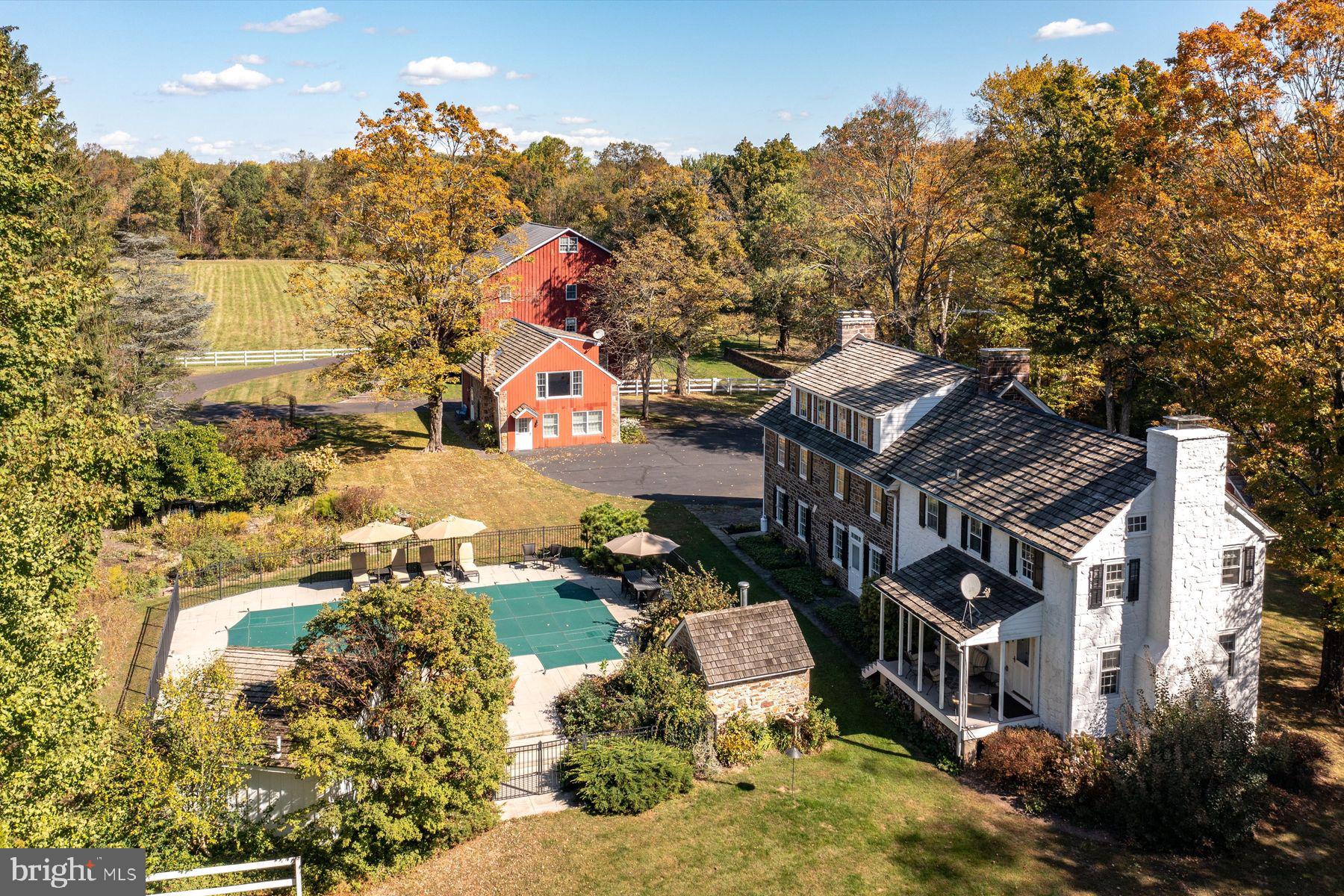 This is the one you’ve been waiting for. Available for the first time in almost 50 years, Green Valley Farm is an excellently maintained estate property enjoying a bucolic Bucks County setting on two lots totaling nearly 25 acres. Just minutes from downtown New Hope and Doylestown, PA, the buildings are set far from the road. Enter along a magnificent tree-lined drive, traverse a charming bridge and the Pine Run creek to arrive at the courtyard bordered by a stone Manor House, Carriage House and a classic Bucks County Bank Barn. The Manor House dates back to 1760 with a massive dressed stone fireplace, 4000 ft.² of living space, and two main bedroom suites. The two-story Carriage House contains up to three bedrooms/2 baths and an expansive rustic living area with charming wood beams and rafters. The classic Bucks County Bank Barn has been finished as an artist studio and gallery in the 1980s, while the first level is perfect for your animal friends.  Garage space is also available in this building. From each building  enjoy magnificent views of fenced and open pastures, the Pine Run, and mature varied treescapes. 
Other buildings on site include a highly usable oversized three-car garage, a classic rectangular pool, a fenced vegetable garden with a simple greenhouse, and working garage. The property is surrounded by 50 acres of preserved land and other large parcels for complete privacy.  The property has two parcels which include the main estate and a 1.88 acre separate building lot.
