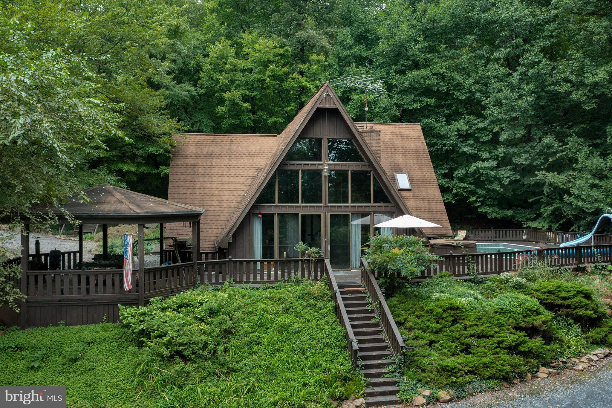 Drive down the private lane to this beautiful A-frame home on 11 acres of wooded paradise.  (Surrounded by clean and Green) 3- car garage with workshop.  Wrap around decking with gazebo, fish pond, inground swimming pool and outside bar for entertaining.  3/4 bedrooms.  Amazing owner's suite with walk in closet, gas fireplace, a hot tub sunroom with another gas fireplace. 7  fireplaces (5 indoor and 2 outdoor fireplaces).  Unbelievable lower level family room with pool room, game room, wet bar and 2nd kitchen.  Spiral staircase.  4-zone heat and Central Air.  2.5 bathrooms.  1st floor laundry.  Amazing vaulted 2-story living room with floor to ceiling windows and stone fireplace.
1st floor family room with wet bar, fireplace, and french door out to pool deck.  Just too much to mention!  You'll love it!!!