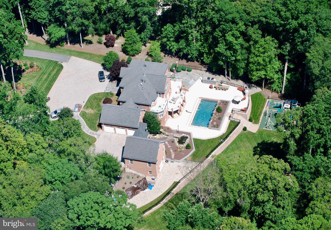 Private and gated, this grand estate is sited on a 2+ acre lot featuring meticulously manicured grounds and a stunning backyard oasis with 40' resort style pool, outdoor kitchen, fireplace and a one of a kind children's play area.  Owner's suite with spa like bath, gas fireplace, balcony and oversize walk-in closet with custom built storage.  A spacious gourmet kitchen opens to family room with gas fireplace and deck.  The kitchen is equipped with state of the art commercial grade 6 burner Dacor updraft cooktop, 2 30" convection ovens, subzero refrigerator and stainless dishwasher.  First floor office with built-ins, finished lower level with custom bar, wine cellar, sauna and fitness room.  Attached 3-car side loading garage, which is climate controlled with heat and air conditioned year round.  The garage floors (Strong Hold Floors) are sealed with 30 year guaranty plus multiple shelving system (Garage Tek) which allows you to organize your garage anyway you like.  The detached 3-car garage with in-law suite has the same features as the attached garage.  This home has privacy and is secured by a complete fenced in yard and camera system that you can view live time 24/7 from anywhere.  The many custom details highlight true luxury living at its best.  Convenient to Washington, DC, Baltimore and Annapolis.