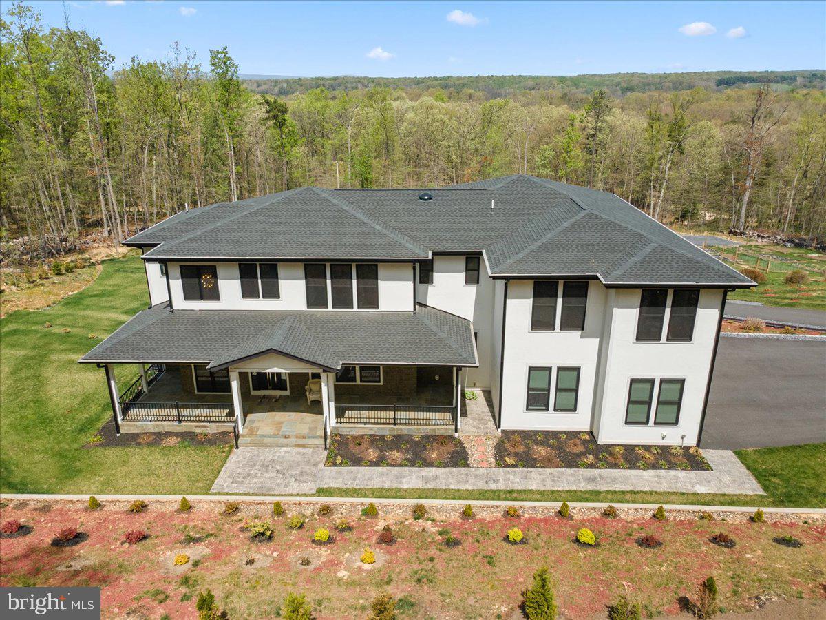 Just a short drive from Washington, D.C., this extraordinary custom estate offers a rare opportunity to enjoy the privacy of a mountain retreat without giving up access to the city. Set on 20 secluded acres, the property delivers the kind of space, scenery, and tranquility that is increasingly hard to find for buyers seeking a true escape from the pace of Northern Virginia and D.C. life. From the home, you can take in sweeping views of the Blue Ridge Mountains, Shenandoah Valley, Skyline Drive, Luray Caverns, and the Shenandoah River, while still enjoying convenient access to I-66 and Dulles Airport.  Proudly built by JGL Construction Company, this impressive residence offers more than 8,000 square feet of thoughtfully designed living space, including 5 bedrooms, 5 full baths, 2 half baths, a 3-car garage, and a fully finished walk-out basement. The home combines grand scale with warmth and livability, featuring hardwood floors throughout, soaring ceilings, recessed lighting, and expansive windows that bring the surrounding landscape into everyday life.  The main level was designed for both elegant entertaining and comfortable daily living. A beautifully appointed gourmet kitchen anchors the home with top-of-the-line appliances, a large quartz island, designer cabinetry, a walk-in pantry, and a separate butler’s pantry. The spacious living and family room, centered around a fireplace, opens to a Trex deck overlooking the natural beauty of the property. A formal dining room, main-level bedroom suite, and flexible bonus room ideal for a home office or private study add to the home’s versatility.  Upstairs, the primary suite offers the feel of a private resort. Thoughtfully set apart, it includes a lounge area, oversized walk-in closets with built-ins, and a spa-like bath with a European soaking tub, dual vanities, and a shower for two. Each additional bedroom is generously sized with its own full bath and walk-in closet, while an upper-level family room or library with built-in shelving creates yet another inviting place to relax and enjoy the views.  The fully finished walk-out basement expands the home’s entertaining potential with a large bedroom suite, wet bar, home theater or media room, half bath, and generous recreation space for hosting, celebrations, or extended stays. Outside, the covered patio, sweeping lawn, and extensive landscaping create a setting that feels more like a private resort than a primary residence.  For D.C.-area buyers seeking a weekend escape, a legacy property, or a full-time residence that offers both luxury and breathing room, this home stands apart. Hunt, hike, boat, fish, and enjoy a resort-style lifestyle right in your own backyard. It is a rare blend of sophistication, privacy, and natural beauty and close enough for convenience, yet far enough away to feel like a world of its own.